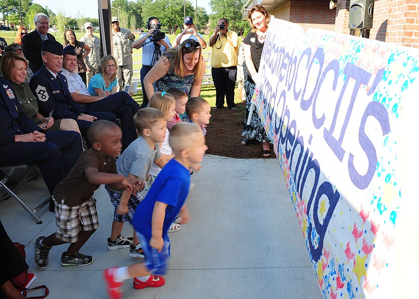 Children run through the welcoming banner and into the Child Development Center II during the grand opening ceremony at Moody Air Force Base, Ga., Aug. 15, 2011. The CDC II accommodates 280 children from infants to preschoolers. (U.S. Air Force photo by Senior Airman Stephanie Mancha/Released)