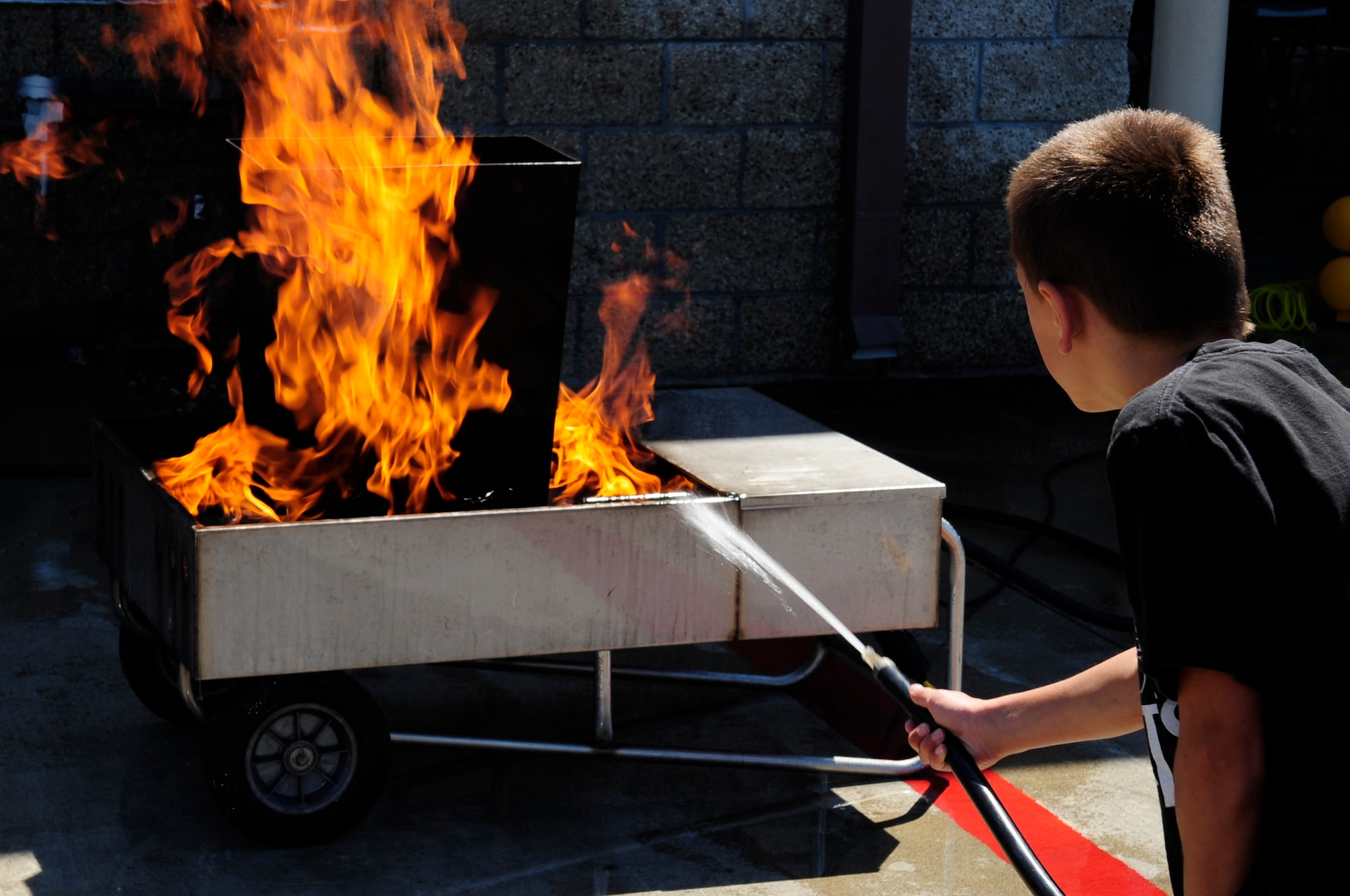 VANDENBERG AIR FORCE BASE, Calif. – Levi Betts uses a fire extinguisher to put out flames during the Kids Fire Camp at Fire Station 2 here Saturday, Aug. 13, 2011. The event allowed 36 children the opportunity to be junior firefighters for a day. (U.S. Air Force photo/Senior Airman Lael Huss)