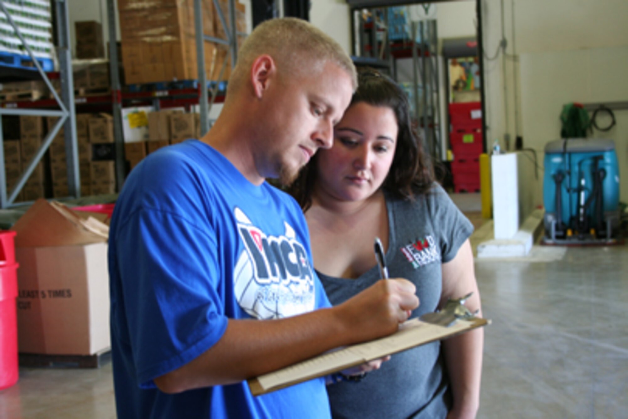 Andrew Pruett, Defense Civilian Personnel Advisory Service, completes the donation log for San Antonio Food Bank food and fund drive coordinator Monica Borrego during the Alamo Federal Executive Board's first Feds Feed Families donation collection day. The next AFEBS donation collection day is Aug. 31. (U.S. Air Force photo/Debbie Gildea)