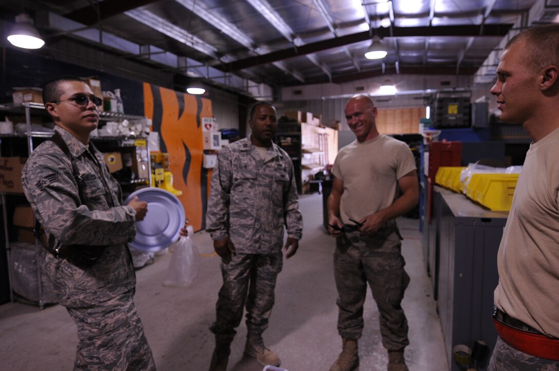 (From far left) Senior Airman Hansel Orozco, chaplain assistant and Chaplain (Capt.) Ralph Elliott, both from 455th Air Expeditionary Wing Chaplain Corps, make a morale visit at another maintenance shop, July 15, 2011, at Bagram Air field, Afghanistan. The two search of opportunities to provide fellow deployed Airmen much-needed relief from the heat, while spreading the word about the flightline Religious Support Team's ministry on Bagram Airfield's east side. Airman Orozco is assigned to the 433rd Airlift Wing (stateside) at Lackland Air Force Base, Texas, where he serves as a chaplain assistant. His Hometown is San Antonio and he attended Oliver Wendell Holmes High School. (U.S. Air Force photo/Senior Airman Krista Rose)
