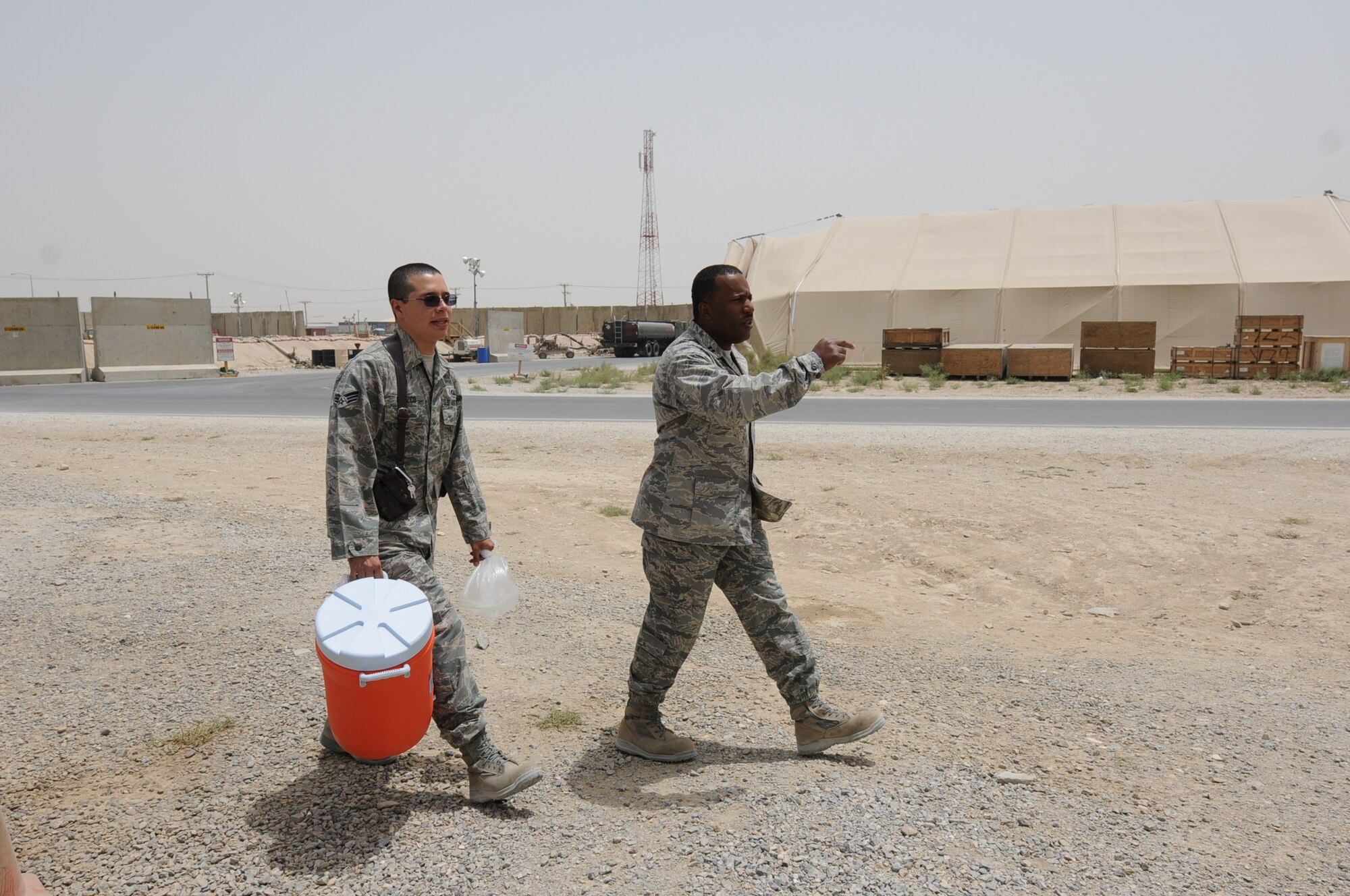 Chaplain (Capt.) Ralph Elliott and Senior Airman Hansel Orozco, chaplain assistant, both from 455th  Air  Expeditionary Wing  Chaplain Corps walk in search of opportunities to provide fellow deployed Airmen much-needed relief from the heat, while spreading the word about the flightline Religious Support Team's ministry on Bagram Airfield's east side, July 15, 2011, at Bagram Air Field, Afghanistan. Airman Orozco is assigned to the 433rd Airlift Wing (stateside) at Lackland Air Force Base, Texas, where he serves as a chaplain assistant. His Hometown is San Antonio and he attended Oliver Wendell Holmes High School.  (U.S. Air Force photo/Senior Airman Krista Rose)