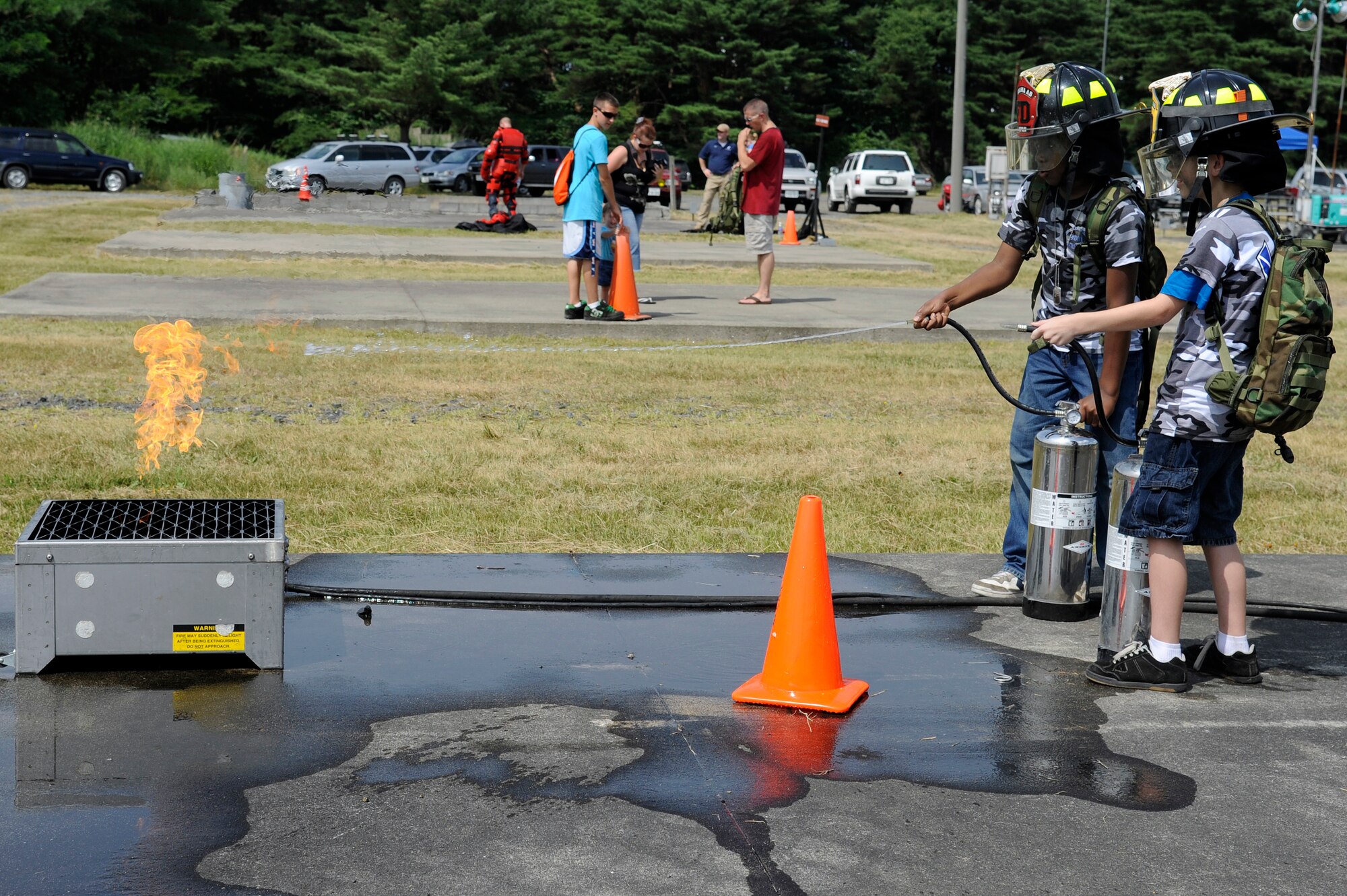 MISAWA AIR BASE, Japan -- Children get an opportunity to put out a fire during fire training while on Operation Children on Deployment Exercise at Camp Defender Aug. 13. While on a simulated deployment the children ran an obstacle course, participated in physical fitness, received fire training, and watched a Security Forces K-9 and Explosive Ordnance Disposal demonstration. (U.S. Air Force photo/Tech. Sgt. Marie Brown)