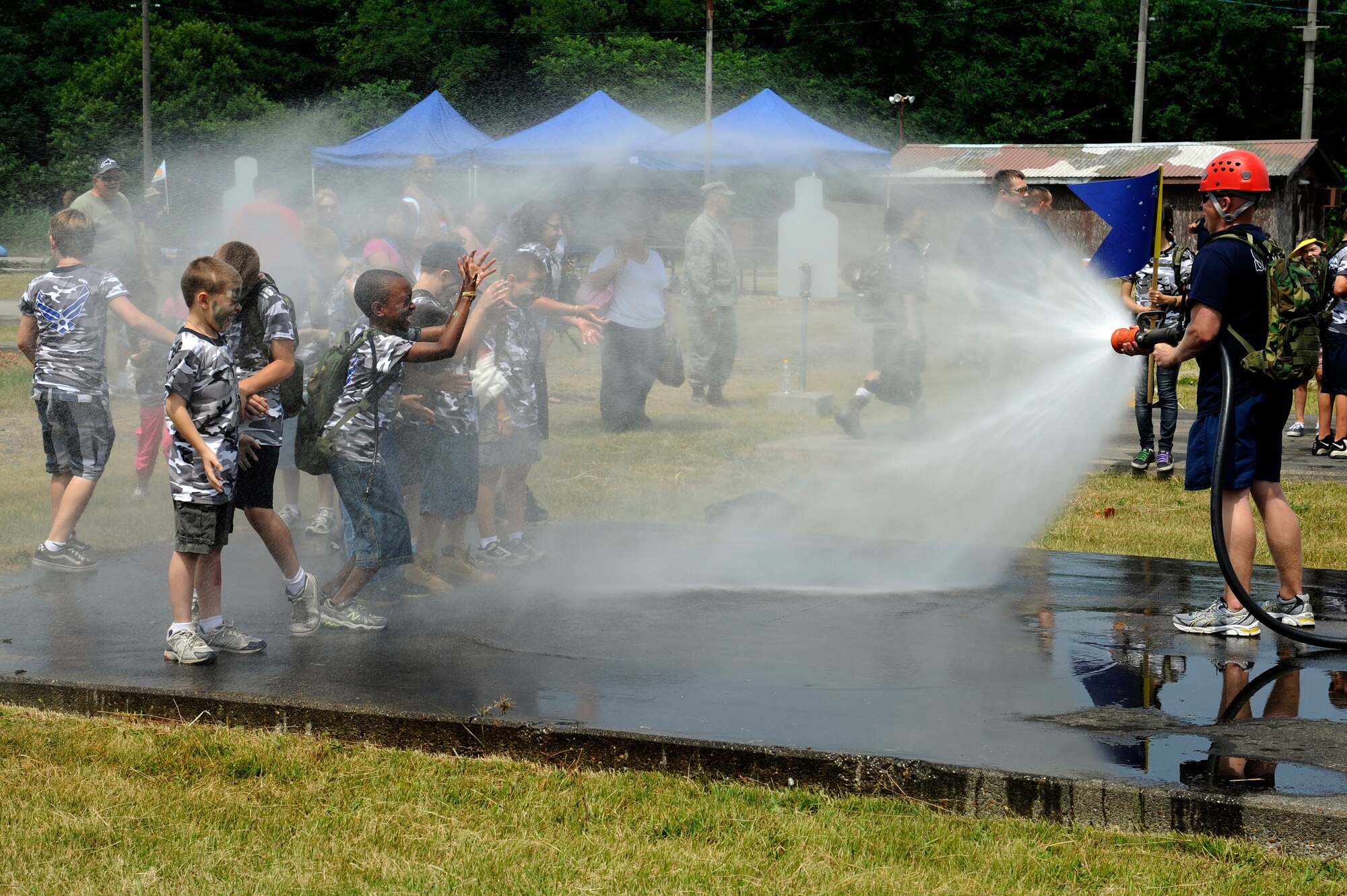 MISAWA AIR BASE, Japan -- Jason DeMoss, right, hoses down the children during Operation Children on Deployment Exercise Aug. 13. Each child was given the opportunity to walk in their parents shoes as they experienced life at a simulated deployed location. (U.S. Air Force photo/Tech. Sgt. Marie Brown)