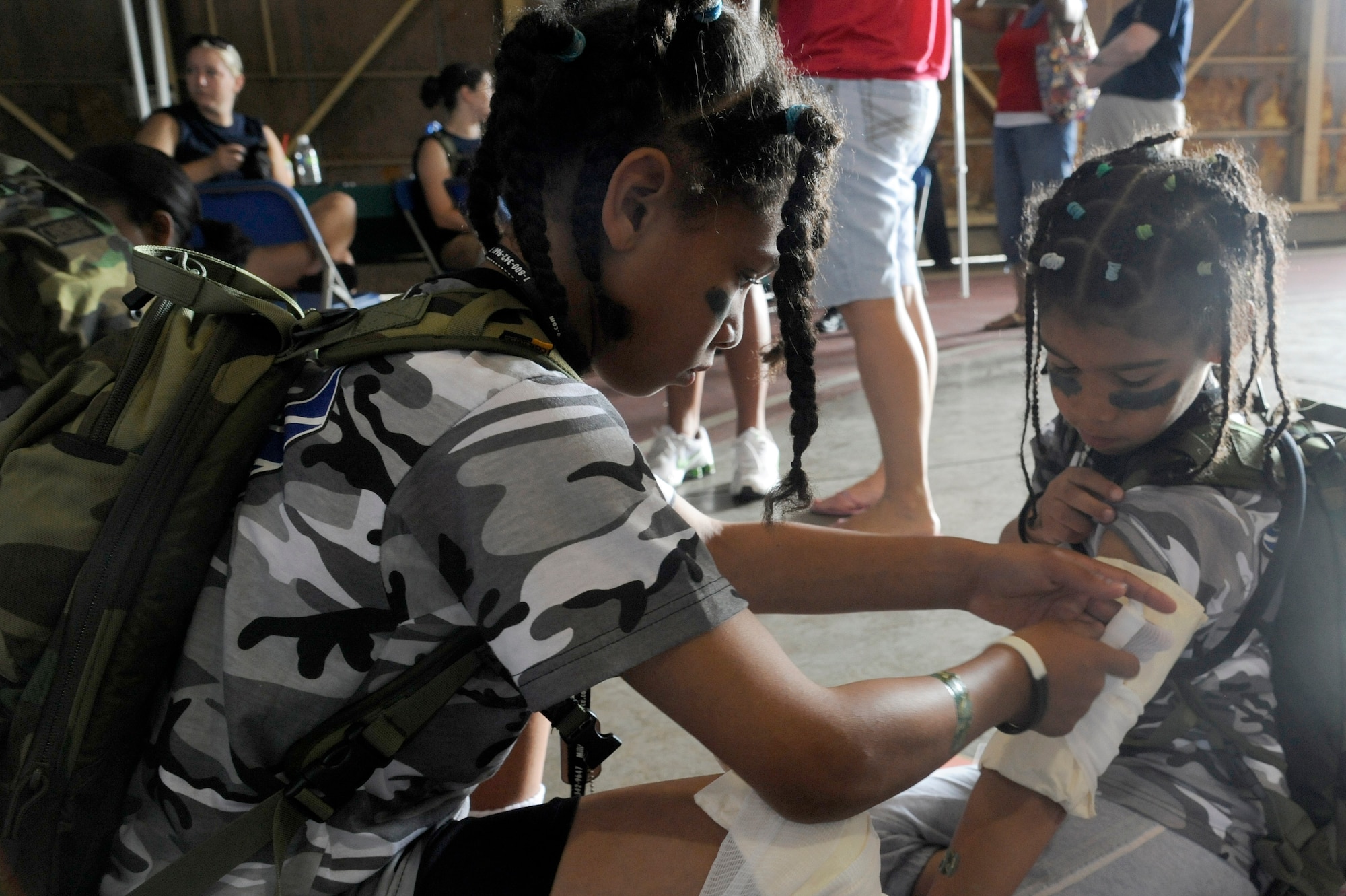 MISAWA AIR BASE, Japan -- Rene Talbert, left, and Mya Talbert, both daughters of Chief Master Sgt. Suzanne Talbert, 35th Mission Support Group, practice self-aid and buddy care on each other during Operation Children on Deployment Exercise Aug. 13. Each child was given a wound in moulage and was trained on how to properly bandage the wound. (U.S. Air Force photo/Tech. Sgt. Marie Brown)