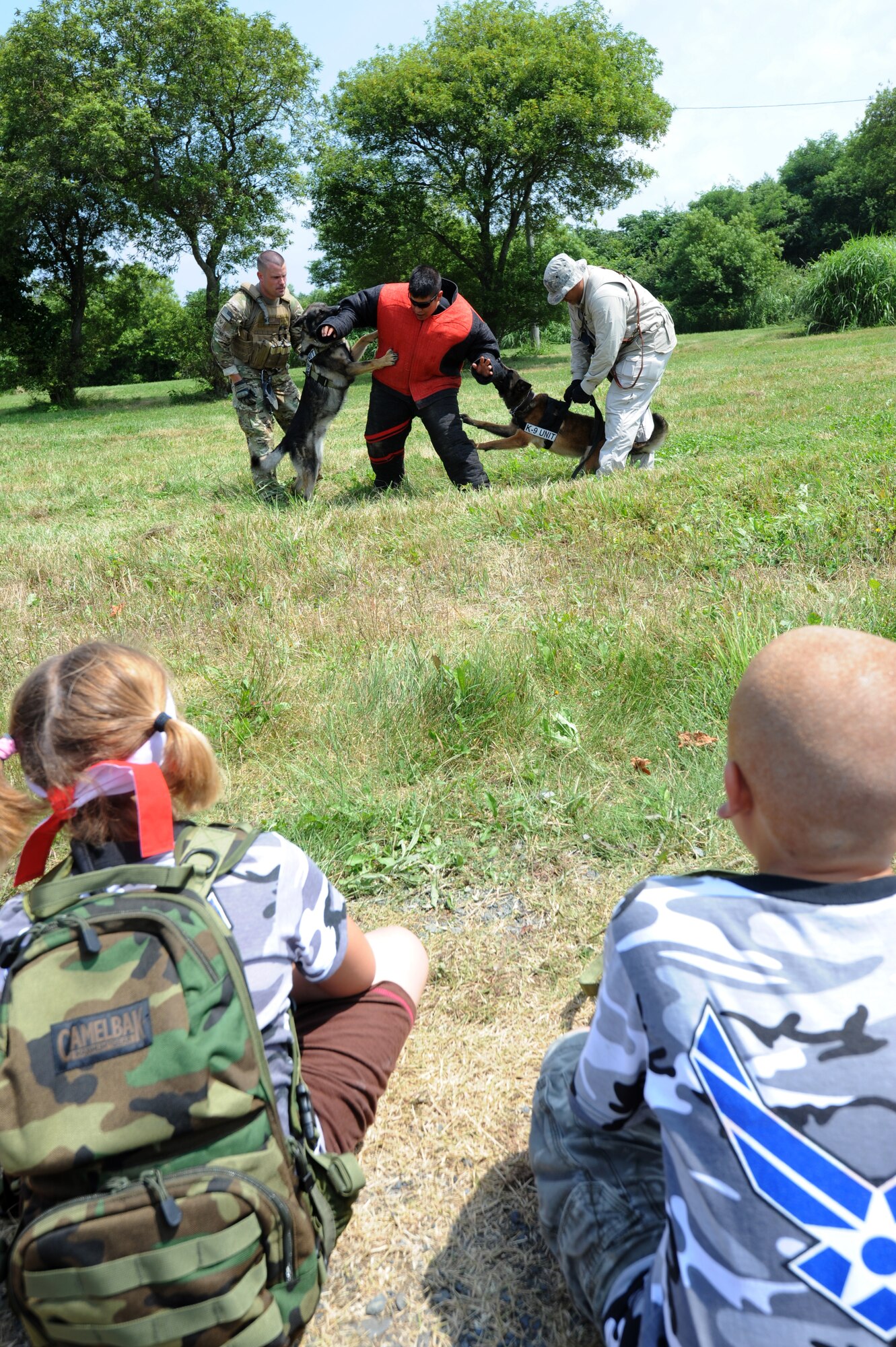 MISAWA Air Base, Japan -- Emerson Retka, daughter of Lt. Col. Anthony Retka, 14th Fighter Squadron, left, and Xavier Garcia, son of Tech. Sgt. Salvador Garcia, 35th Maintenance Operations Squadron, right, watch as Staff Sgt Martin Campos, 35th Security Forces K-9 handler, is attacked by two working dogs Aug. 13.  Staff Sgt. Michael Stevens and military working dog Karo, left , work with Staff Sgt. Francis San Luis and military working dog Didi to apprehend the suspect during Operation Children on Deployment Exercise.  (U.S. Air Force photo/Staff Sgt. April Quintanilla)