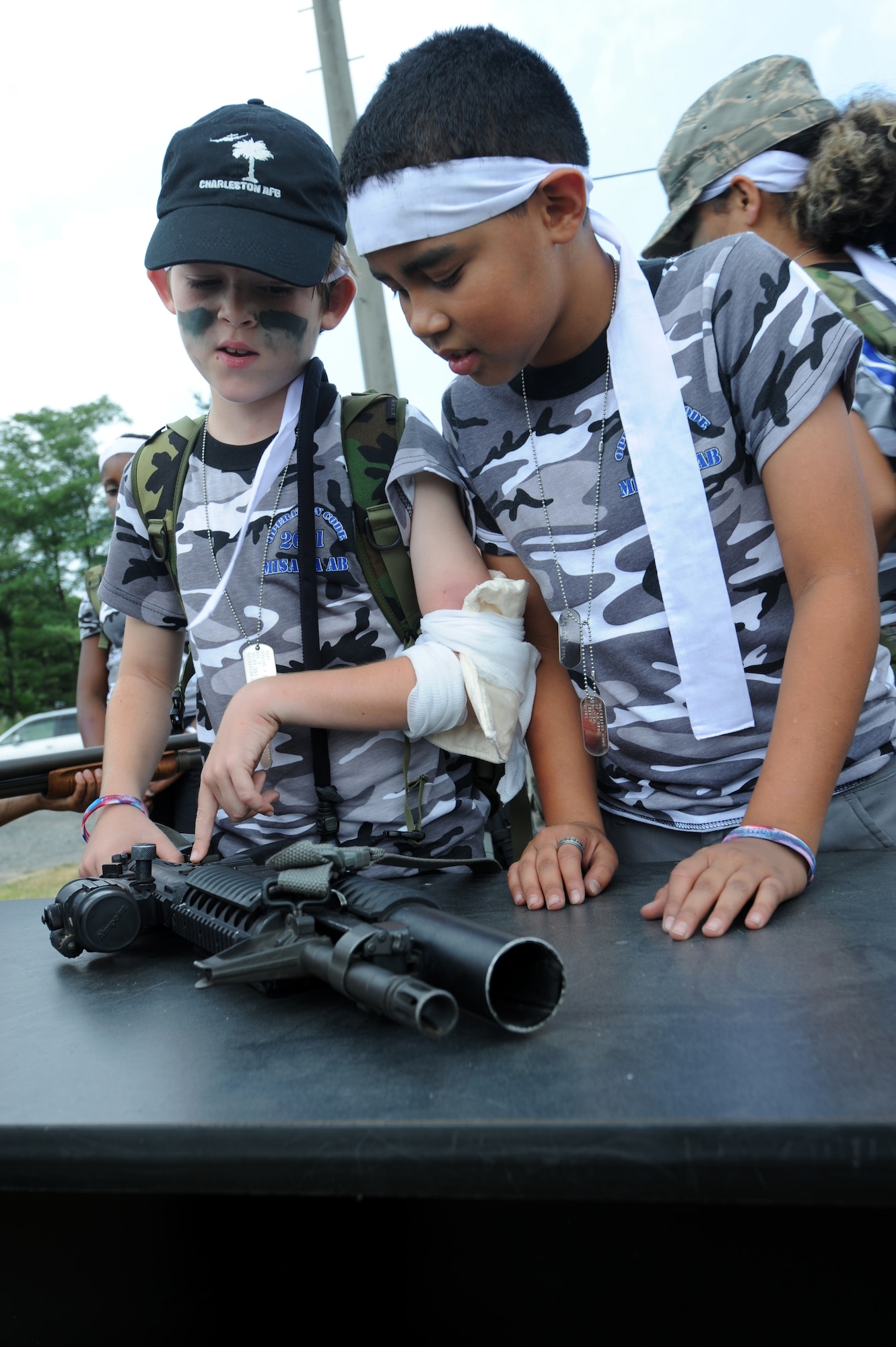MISAWA Air Base, Japan -- Robert Bare III, son of Master Sgt. Maria Bare 35th Fighter Wing Staff, explains to Xavier Muniz, son of Staff Sgt. April Quintanilla, 35th Fighter Wing Staff, the functions of the M-203 Grenade Launcher Aug. 13.  Robert and Xavier participated in Operation Children on Deployment Exercise and were able to experience the side of the military their mom's work in.   (U.S. Air Force photo/Staff Sgt. April Quintanilla)