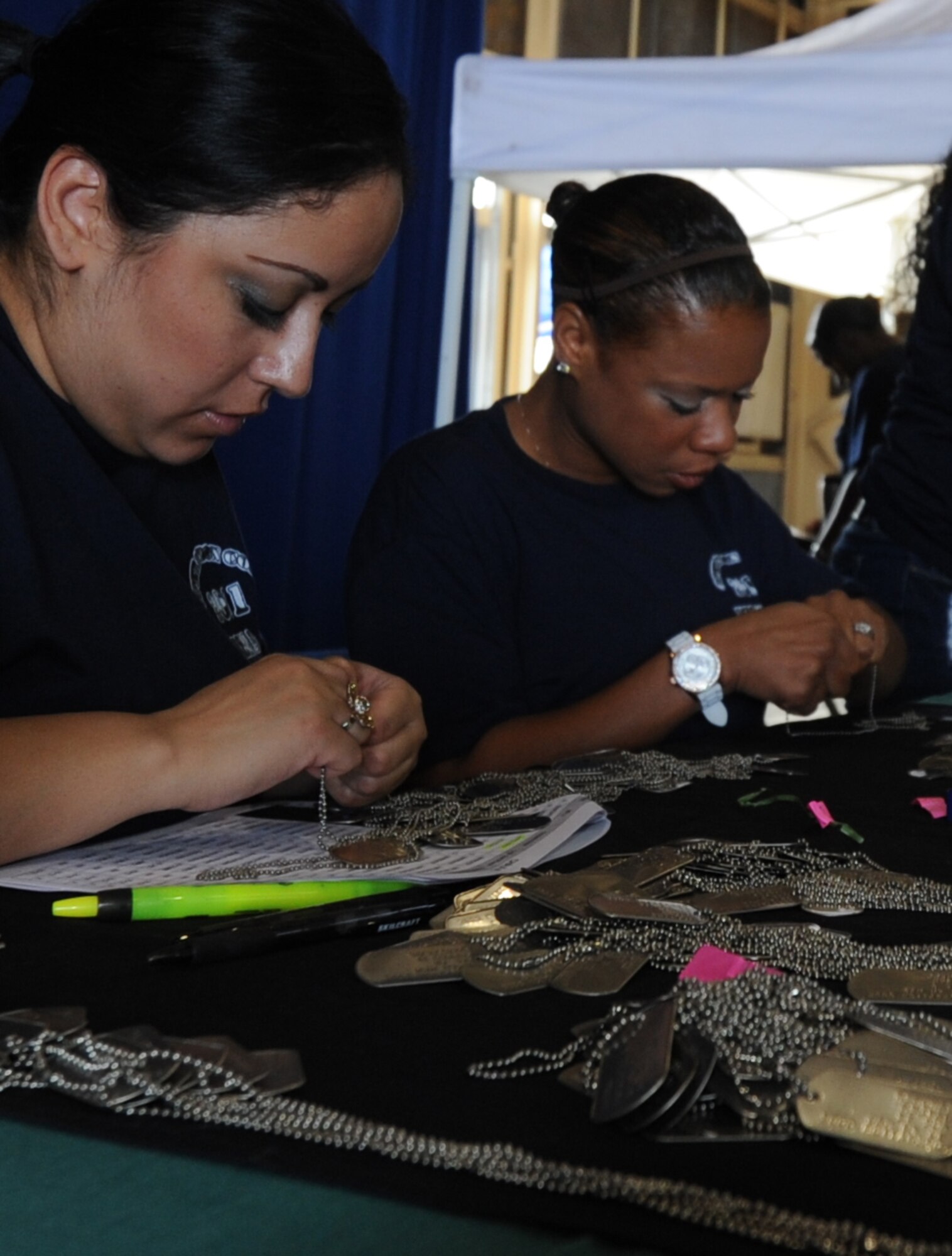 MISAWA Air Base, Japan -- Amanda Munoz, left, and Tabitha David-Williamson,  right, unravel dog tags to hand them out to the kids participating in Operation Children On Deployment Exercise Aug. 13.  This is the second year Misawa Air Base has held Operation CODE and more than 150 children of the base participated.  (U.S. Air Force photo/Staff Sgt. April Quintanilla)