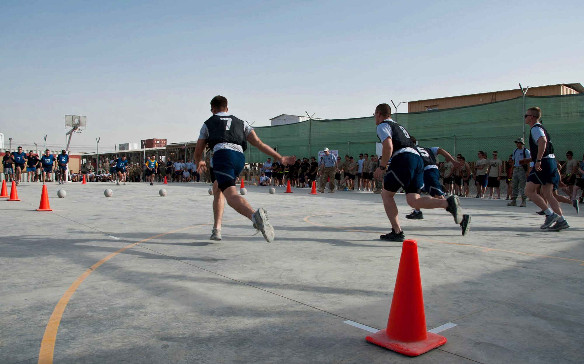 KANDAHAR AIRFIELD, Afghanistan -- Teams sprint to half court for dodgeballs during the dodgeball tournament at the boardwalk Aug. 13, 2011. The tournament included 28 teams from various units around KAF. Volunteers officiated the tournament, which was sponsored by the base’s USO. (U.S. Air Force photo by Senior Airman David Carbajal)