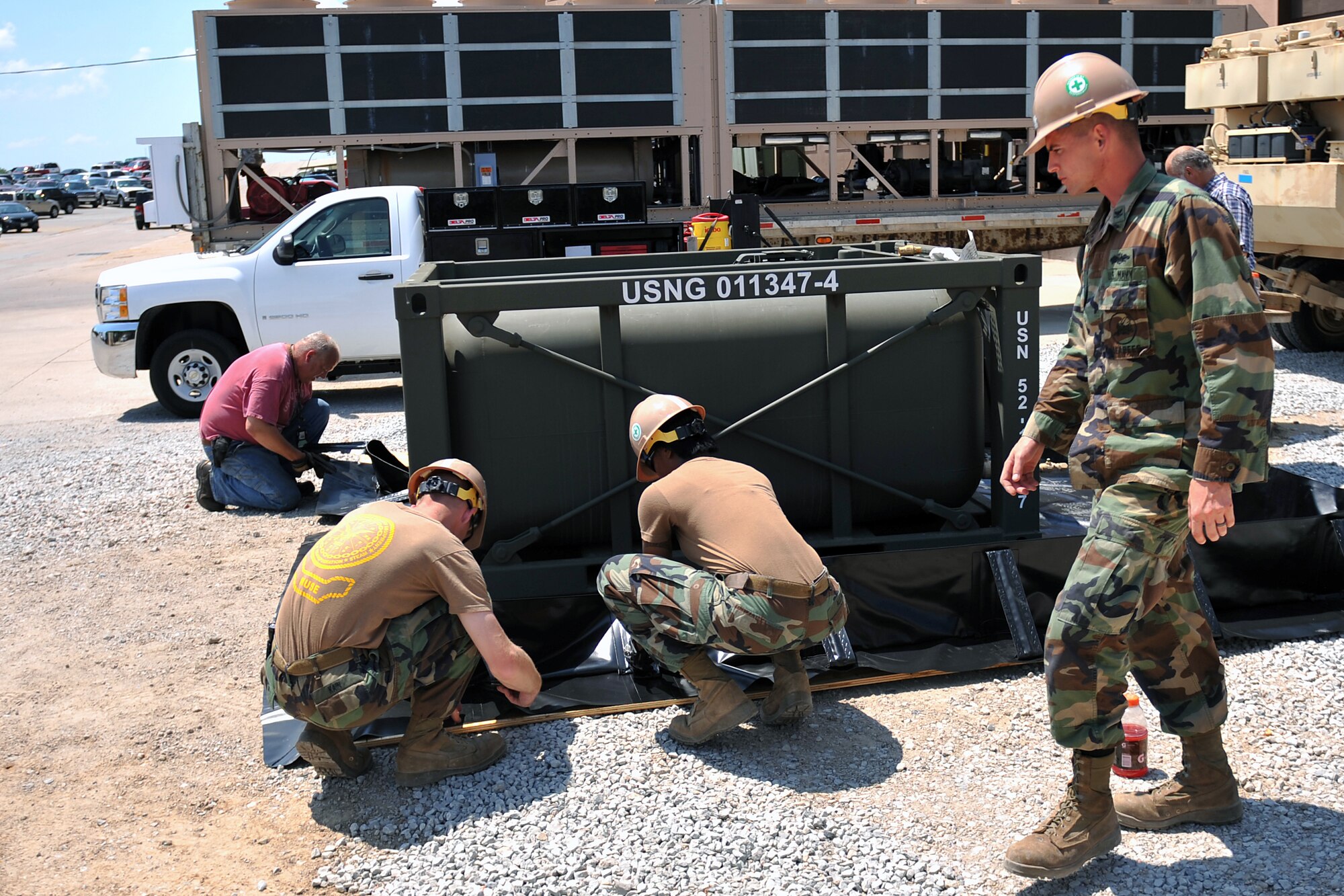 Petty Officer Second Class Cole Einhaus, a utilitiesman with a Mobile Utilities Support Equipment team from Port Hueneme, Calif., watches on as other MUSE team members and power production technicians from the 55th Civil Engineer Squadron here prepare a secondary containment for a fuel tank on July 19 at Offutt Air Force Base, Neb. The MUSE team was here from July 18-27 to install a 3.2 megawatt power plant in conjunction with a 5000 KVA substation. (Air Force photo by Jeff Gates)