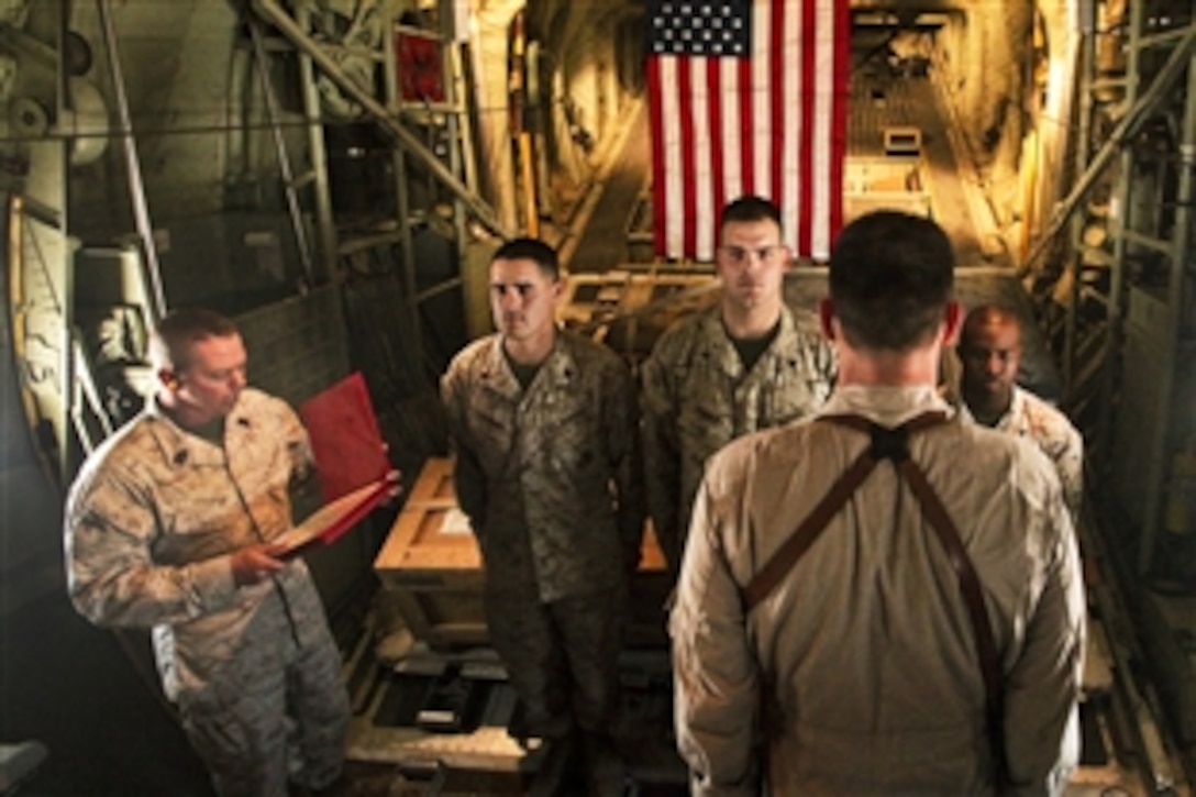 U.S. Marine Corps Sgt. Marc Longoria, left, Cpl. Michael Prince, center, and Cpl. Shawn Rose, re-enlist in a KC-130J Hercules in the skies over Afghanistan, Aug. 13, 2011. Longoria and Prince are powerline mechanics with Marine Attack Squadron 513. Rose is an avionics technician.