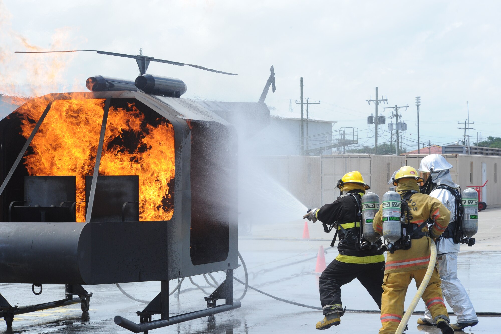 Mr. Renau Andrade (left) and Mr. Mauricio Alvarez, Costa Rican firefighters, extinguish a fire in a mock helicopter with pointers from Staff Sgt. Steven Beene, 612th Air Base Squadron firefighter, during an exercise at Soto Cano Air Base, Honduras, Aug. 16, 2011. The exercise, called Central America Sharing Mutual Operational Knowledge and Experiences or CENTAM SMOKE, allows U.S. and Honduran firefighters four days of team-building training. (U.S. Air Force photo/Tech. Sgt. Matthew McGovern) 
