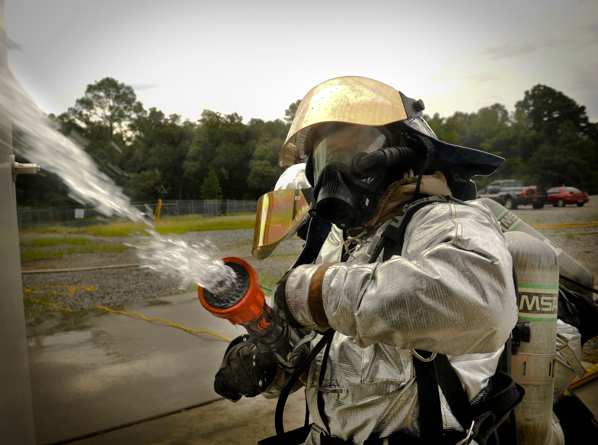 U.S. Air Force Airman 1st Class Elijah Johnson, 23rd Civil Engineer Squadron firefighter, sprays water into a simulated burning building during a phase II operational readiness exercise (ORE) at Moody Air Force Base, Ga., Aug. 16, 2011. Airmen from the 23rd CES partnered in two-man teams to keep a weapons storage building, located next to the burning building, from catching on fire. (U.S. Air Force photo by Airman 1st Class Joshua Green/Released)
