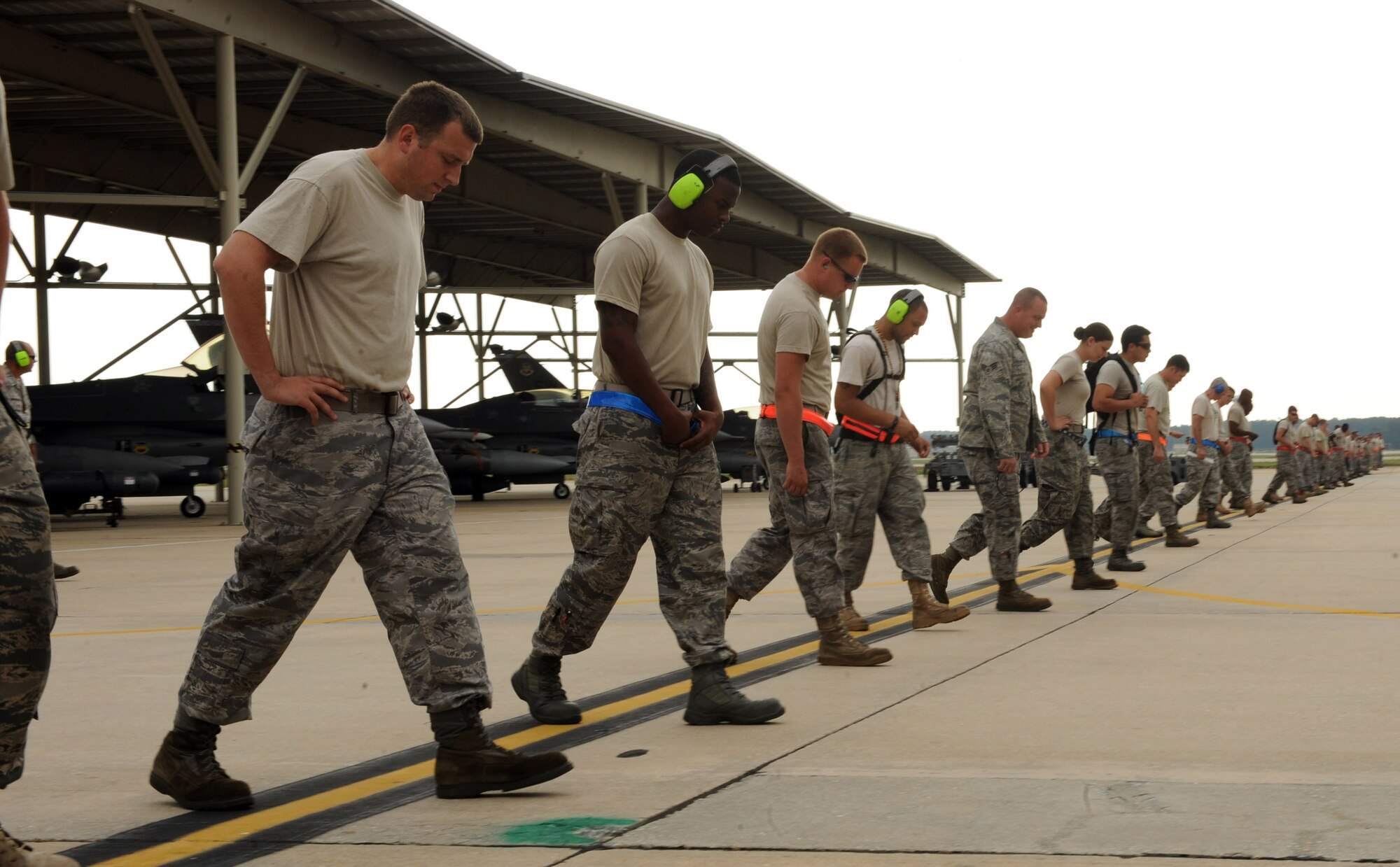 Members from the 55th Fighter Squadron walk the Shaw flight line during a foreign object debris walk, Shaw Air Force Base, S.C., Aug. 12, 2011. Green Flag West is an exercise that is held at Nellis AFB, Nev., and takes place ten times a year to prepare aircraft and crews for ground support combat training. (U.S. Air Force photo/Airman 1st Class Tabatha L. Duarte)(Released)