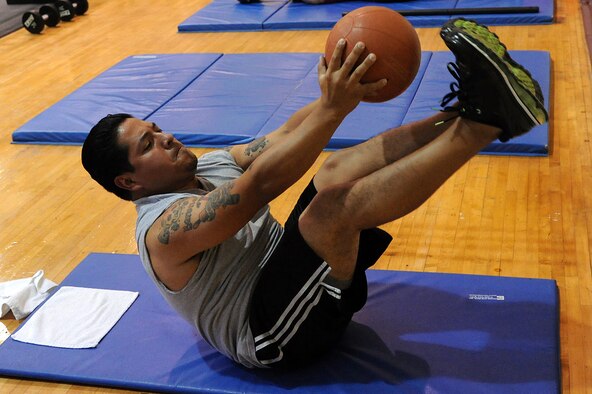 SEYMOUR JOHNSON AIR FORCE BASE, N.C.- Staff Sgt. Alejandro Castillo reaches to touch his toes with a medicine ball during a V-shape abdominal exercise here Aug. 15, 2011. The V-shape abdominal exercise tightens abdominal muscles and strengthens the core.  Castillo, a native of San Antonio, has lost 15 pounds and improved his overall fitness while participating in boot camp for a month. (U.S. Air Force photo by Senior Airman Whitney Lambert/Released)