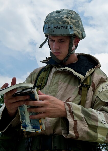 Airman 1st Class Cody Hamilton, of the 96th Communications Squadron, consults his Airman’s manual during the Phase II exercise Aug. 10 at Eglin Air Force Base, Fla.  More than 100 Airmen braved black flag conditions (and rain) in chemical gear and gas masks to execute self-aid and buddy care, security and chemical attack avoidance missions.  The Phase II was part of a large week-long Operational Readiness Exercise on base.  (U.S. Air Force photo/Samuel King Jr.)