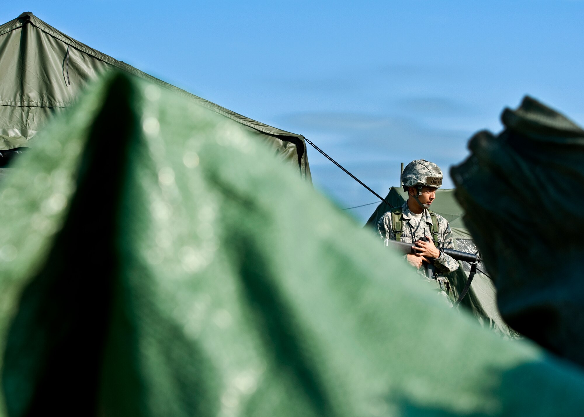 Airman Michael Bautista, of the 96th Logistics Readiness Squadron, guards the Charlie flight tent during the Phase II exercise Aug. 10 at Eglin Air Force Base, Fla.  More than 100 Airmen braved black flag conditions (and rain) in chemical gear and gas masks to execute self-aid and buddy care, security and chemical attack avoidance missions.  The Phase II was part of a large week-long Operational Readiness Exercise on base.  (U.S. Air Force photo/Samuel King Jr.)