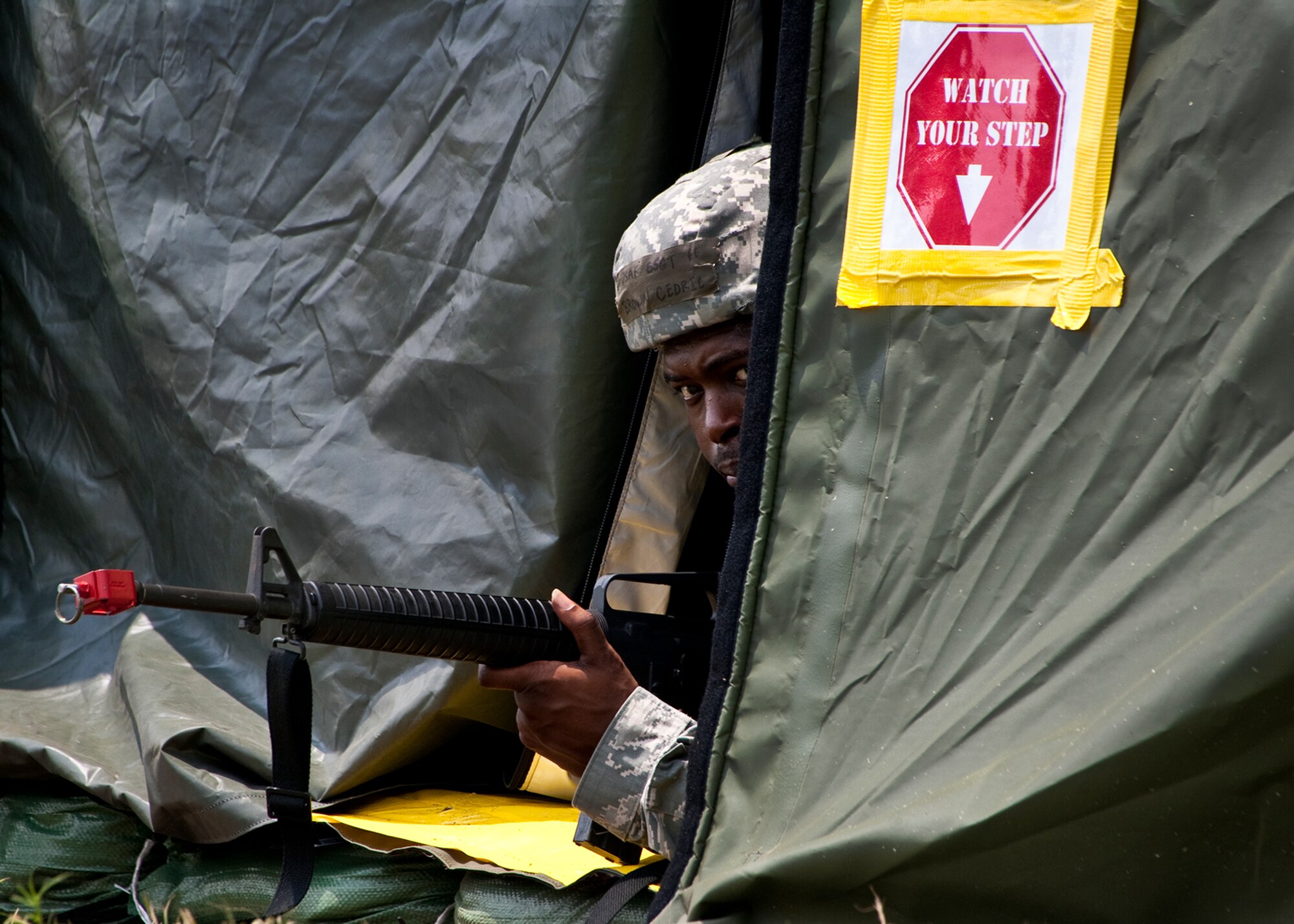 Staff Sgt. Cedric Brown, of the 96th Force Support Squadron, checks outside of the tent after a simulated attack during the Phase II exercise Aug. 10 at Eglin Air Force Base, Fla.  More than 100 Airmen braved black flag conditions (and rain) in chemical gear and gas masks to execute self-aid and buddy care, security and chemical attack avoidance missions.  The Phase II was part of a large week-long Operational Readiness Exercise on base.  (U.S. Air Force photo/Samuel King Jr.)