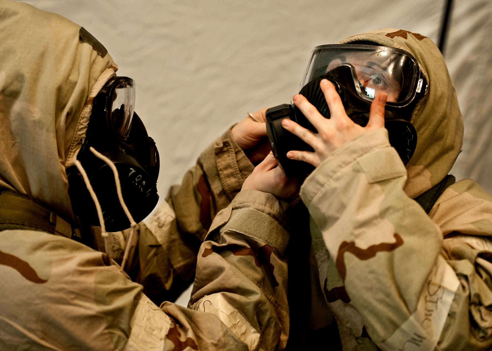 A wingman helps her fellow Airman secure her J-list suit during a simulated mission oriented protective posture level 4 attack at the Phase II exercise Aug. 12 at Eglin Air Force Base, Fla.    More than 100 Airmen braved black flag conditions in chemical gear and gas masks to accomplish their missions.  The Phase II was part of a large week-long Operational Readiness Exercise on base.  (U.S. Air Force photo/Samuel King Jr.)