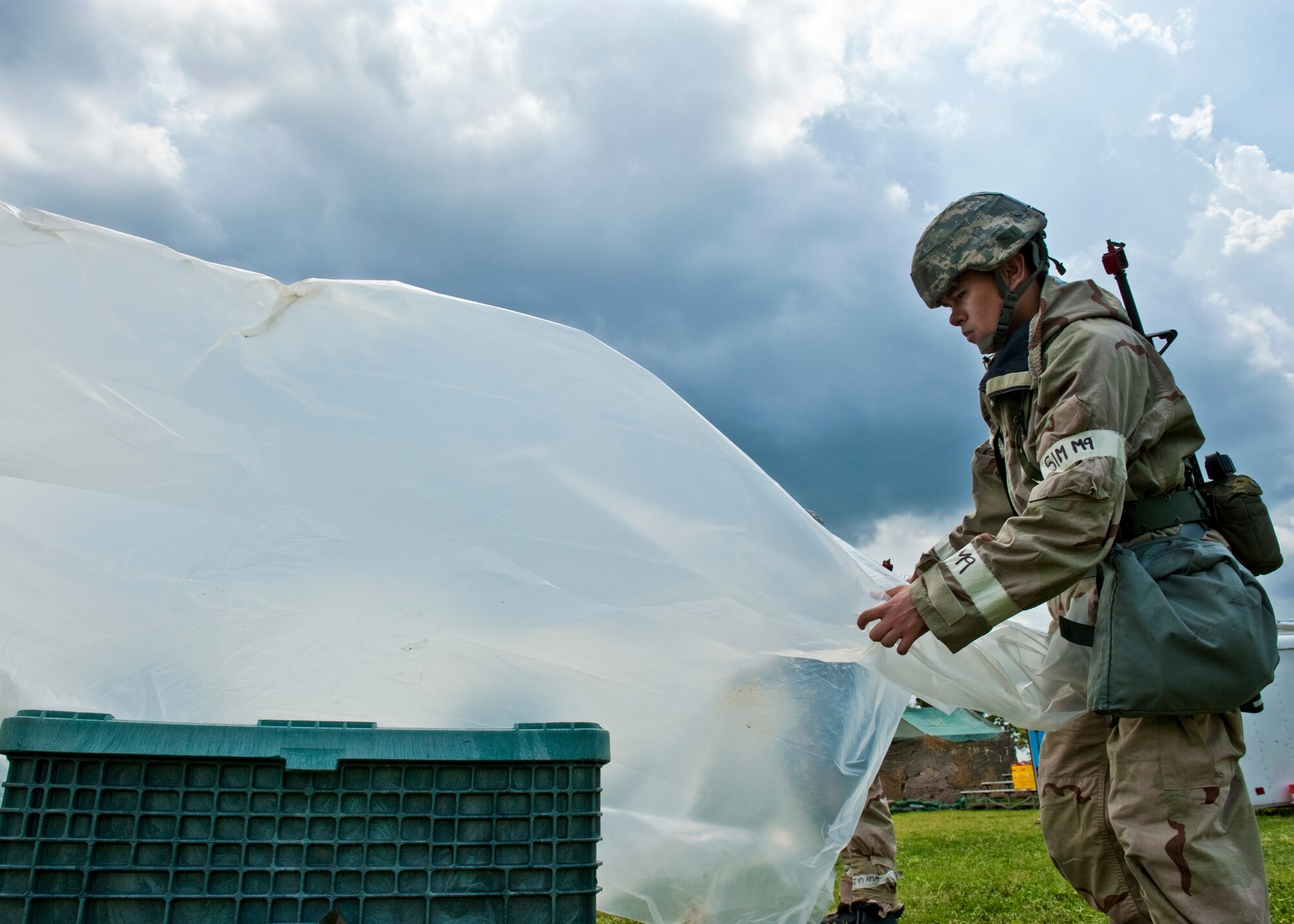 Airman 1st Class Andrew Hull, 96th Logistics Readiness Squadron, covers a valuable asset as part of contamination avoidance measures during the Phase II exercise Aug. 10 at Eglin Air Force Base, Fla.  More than 100 Airmen braved black flag conditions in chemical gear and gas masks to accomplish their missions.  The Phase II was part of a large week-long Operational Readiness Exercise on base.  (U.S. Air Force photo/Samuel King Jr.)