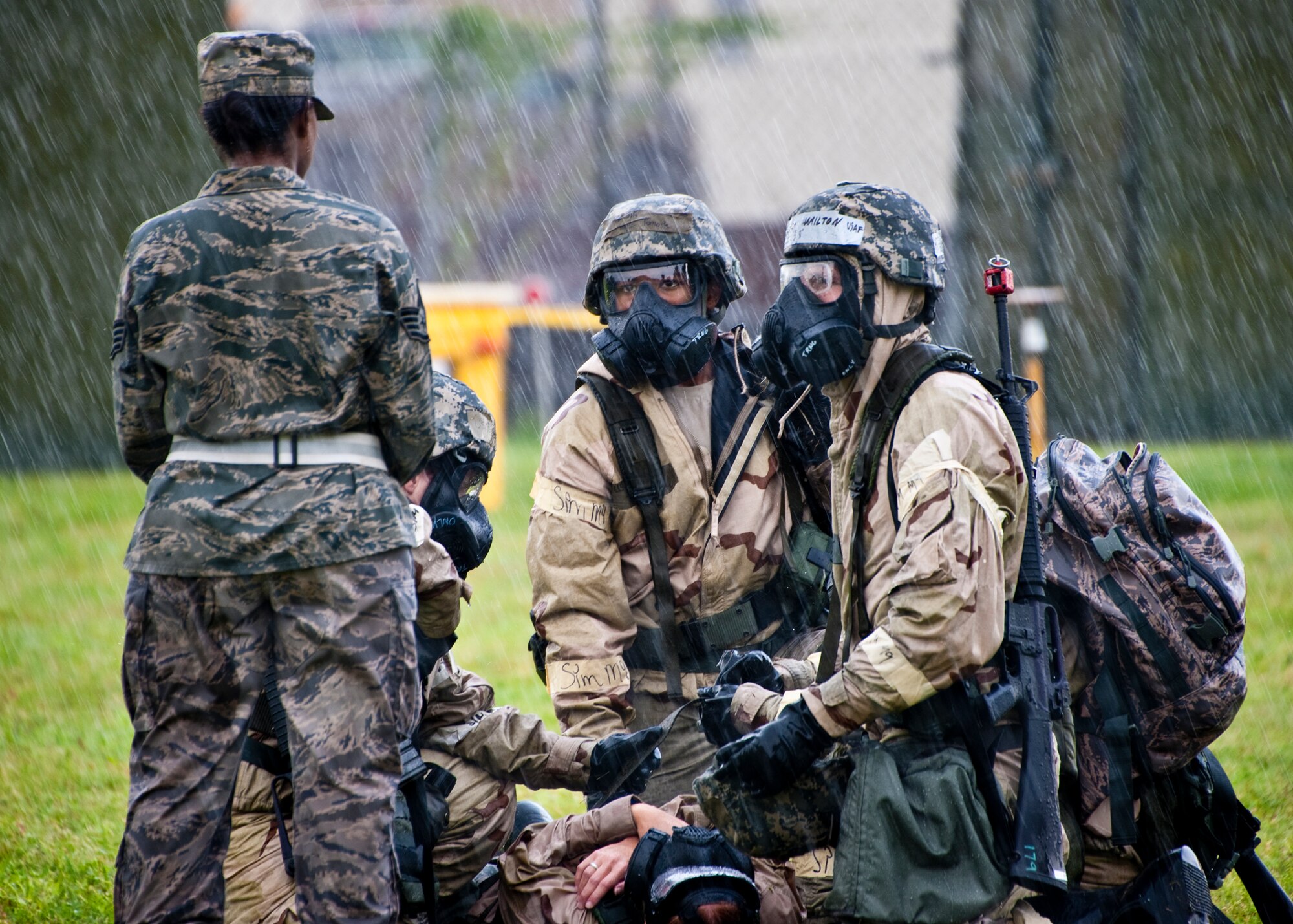 Airmen talk with a 96th Medical Group evaluator through a sudden rainstorm during the Phase II exercise Aug. 10 at Eglin Air Force Base, Fla.  More than 100 Airmen braved black flag conditions (and rain) in chemical gear and gas masks to execute self-aid and buddy care, security and chemical attack avoidance missions.  The Phase II was part of a large week-long Operational Readiness Exercise on base.  (U.S. Air Force photo/Samuel King Jr.)