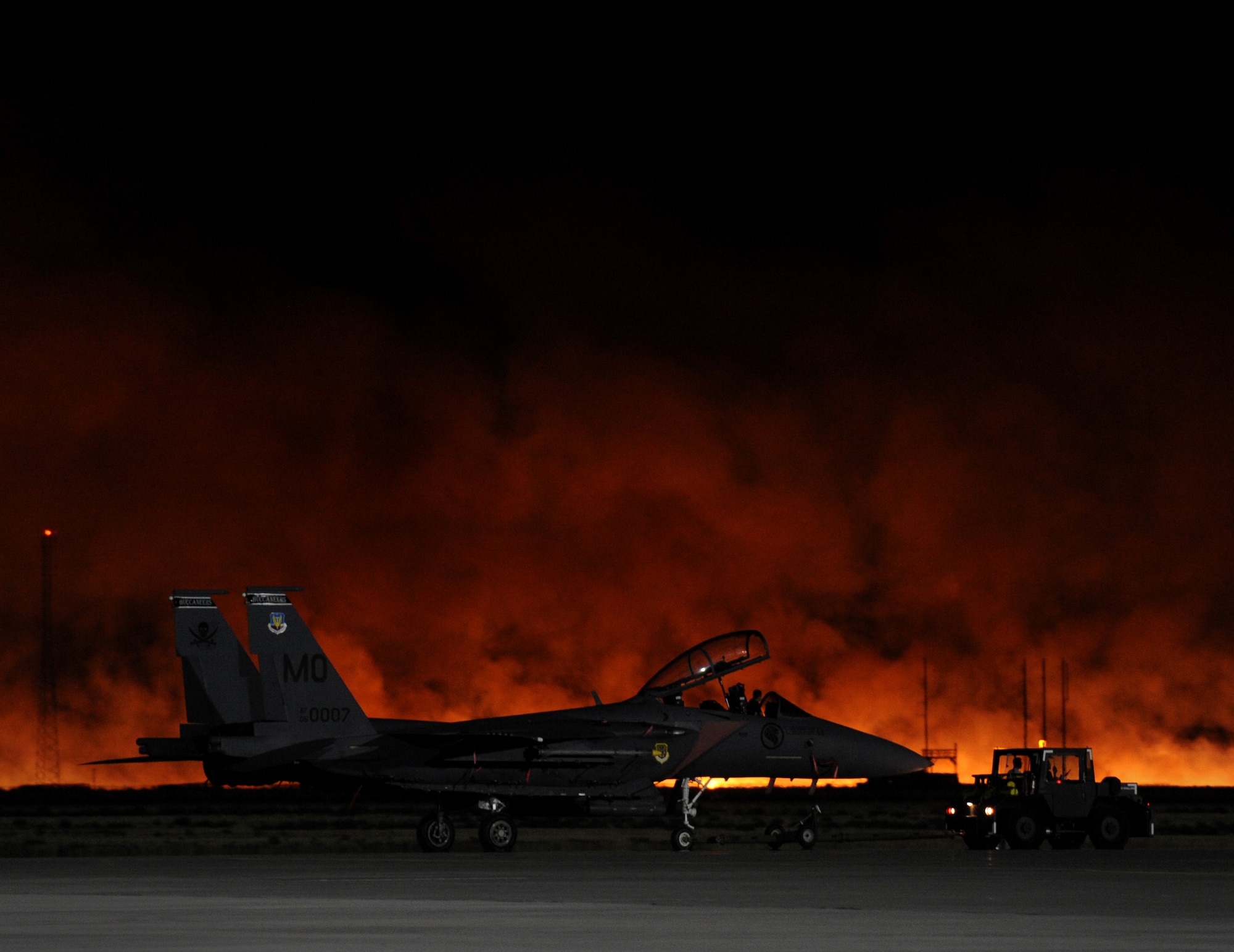A brush fire lights up the evening sky behind a F-15SG assigned to the Republic of Singapore air force at Mountain Home Air Force Base, Idaho, Aug. 15, 2011. Flight line activity, to include all flying operations, were stopped and personal evacuated from flight line buildings as the fire approached the base. A building containing navigation equipment on the airfield may have sustained some minor damage. No other damage was reported. The fire burned approximately 3,000 acres, including five acres on the northwest corner of the base. (U.S. Air Force photo by Staff Sgt. Gina Chiaverotti-Paige)