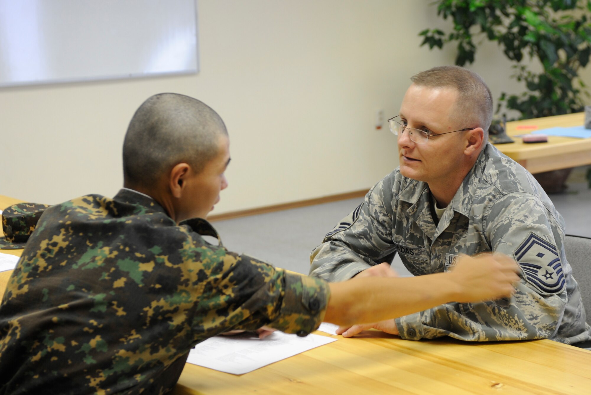 Senior Master Sgt. James Wadas (right) explains what the diamond in his rank means to a soldier from Koi Tash, Kyrgyzstan, during a noncommissioned officer school language lab Aug. 11. Wadas is deployed as the 376th Expeditionary Mission Support Group first sergeant from Goodfellow Air Force Base, Texas. (U.S. Air Force photo/Chief Master Sgt. James Lucas)