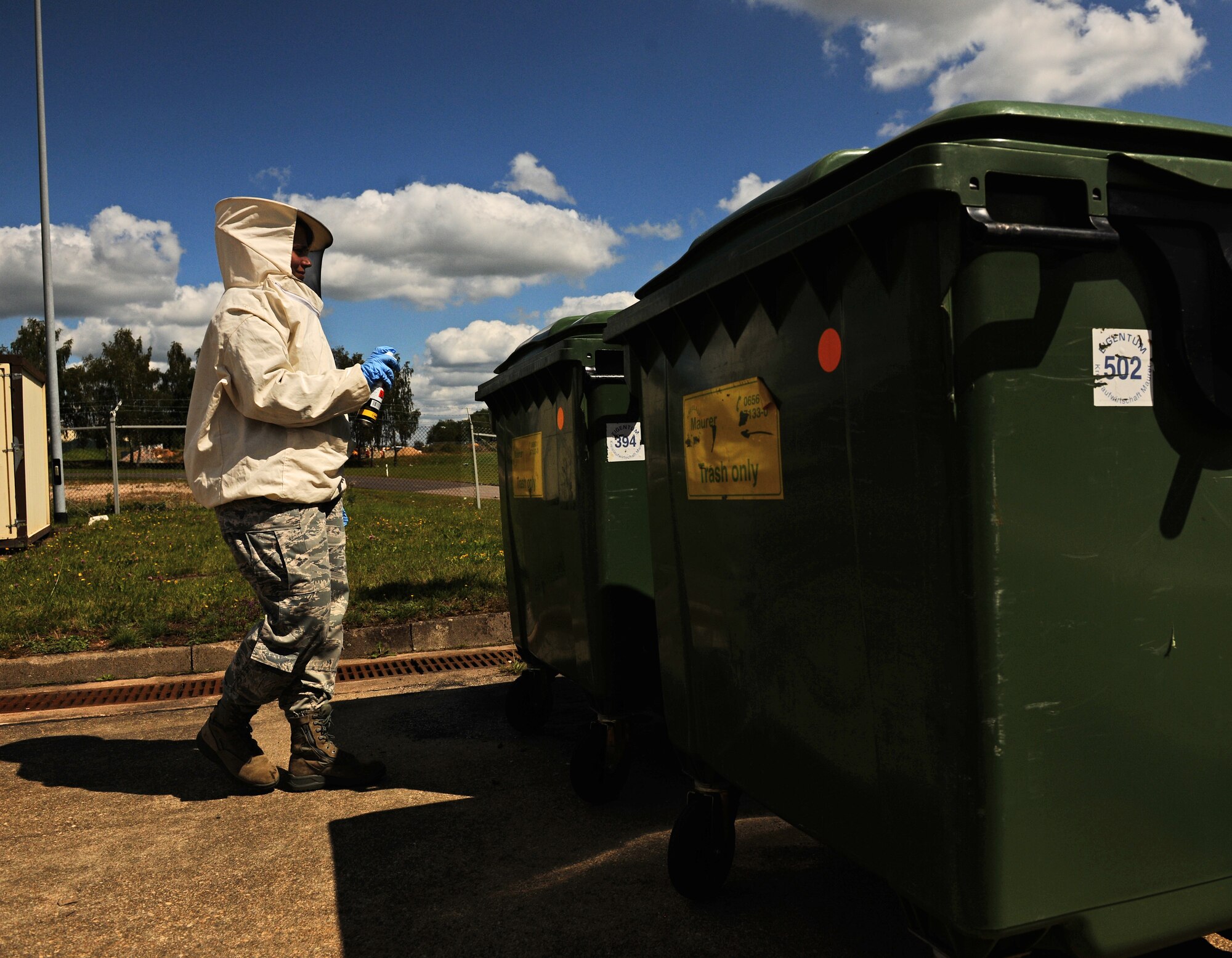 SPANGDAHLEM AIR BASE, Germany -- Airman 1st Class Elizabeth McCasland, 52nd Civil Engineer Squadron pest controller, checks a trash bin for a wasp nest here Aug. 15. The 52nd Civil Engineer Squadron Pest Management Flight specializes in ridding the base of insects, rodents and animals that may pose harm to base members and daily mission operations. (U.S. Air Force photo/Staff Sgt. Nathanael Callon)