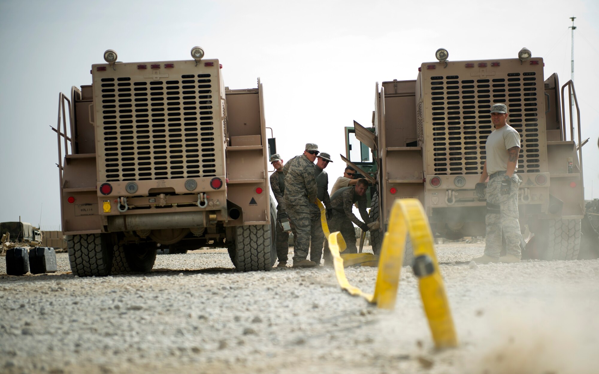 Airman 1st Class Chris Ladue, firefighter on the crash, fire and rescue team, unreels a fire hose as his team looks on, Aug. 14, 2011 at Forward Operating Base Apache, in Qalat, Afghanistan.  The team provides CFR so that aircraft can land on the local dirt landing zone.  (U.S. Air Force photo by Staff Sgt. David Salanitri)