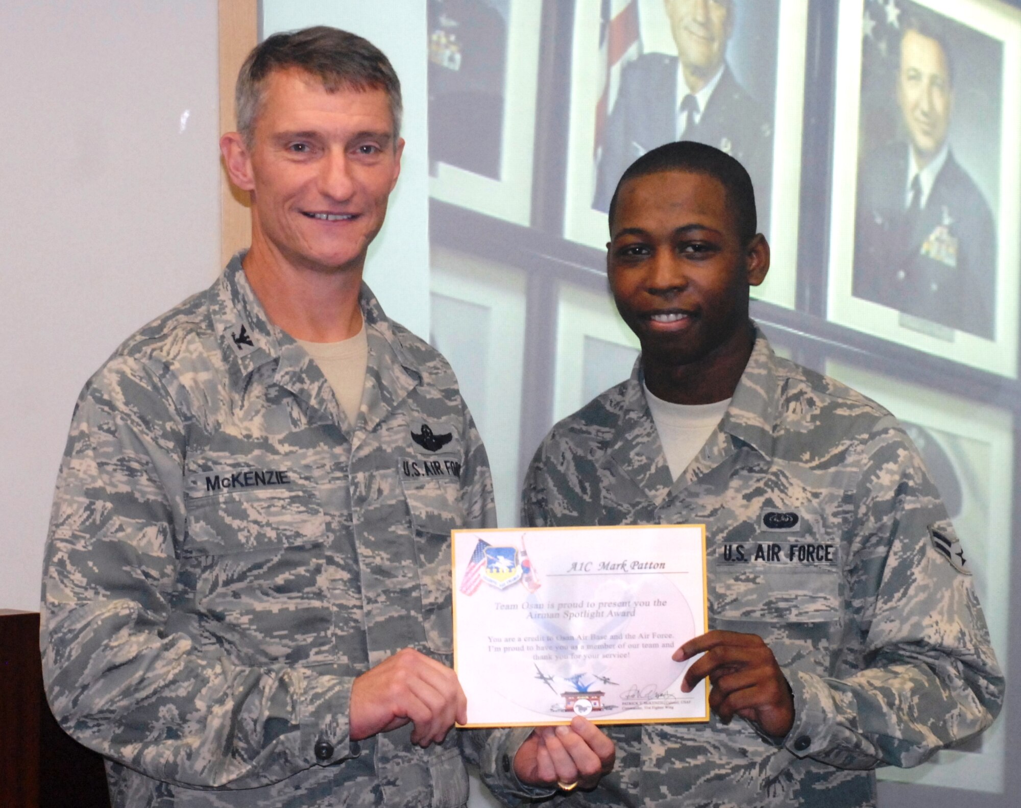 Col. Patrick McKenzie, 51st Fighter Wing commander, awards Airman 1st Class Mark Patton, 51st Fighter Wing staff, with a certificate recognizing him as the Airman Spotlight of the week August 16, 2011. (U.S. Air Force photo/Senior Master Sgt. Stuart Camp)
