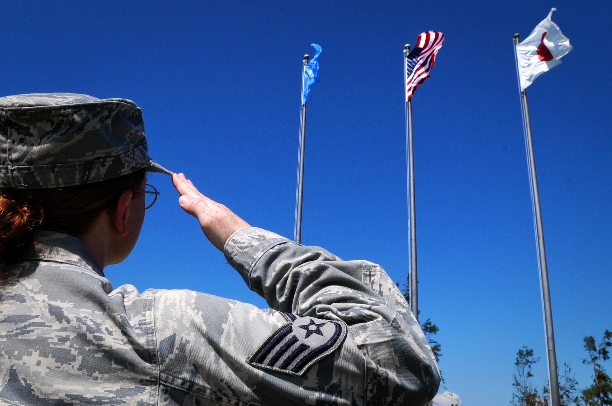 A Kadena Airman salutes the American and Japanese flags at the 18th Wing Headquarters building on Kadena Air Base, Japan, Aug. 16. Though the protocol for respecting these signals is standard for U.S. military bases around the world, there are different sets of procedures for service members to follow depending on whether the flag is flying half of each day or indefinitely. Because the flags on Kadena fly for 24 hours, Air Force instructions don’t mandate actions to be taken here during “Reveille,” “To the Colors” or “Taps,” but only during “The Star Spangled Banner” and the “Kimigayo.” (U.S. Air Force photo/Airman 1st Class Maeson L. Elleman)