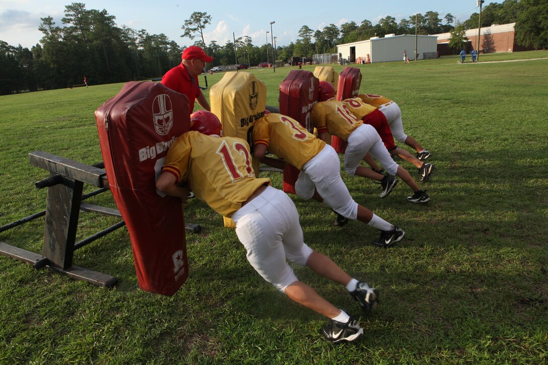 Lejeune High School assistant football coach Mike Gardner practices Big Bruiser drills with his football players Aug. 10 during practice behind LHS aboard Marine Corps Base Camp Lejeune. The Lejeune High School football team has set high expectations for this season and plan on going above .500 for the first time in nearly six years.