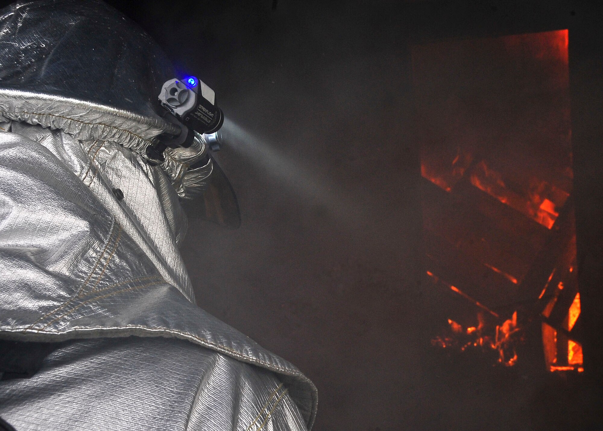 A firefighter from the 51st Fighter Wing Civil Engineer Squadron examines a structural fire during Silver Flag, Aug. 16. During the training Airmen were placed up against the challenge of wearing their JS-List suit underneath their fire fighting suit which increase their body core temperature  by 10 degrees which forces them to rely on team work.  (U.S. Air Force Photo by/ Senior Airman Adam Grant)