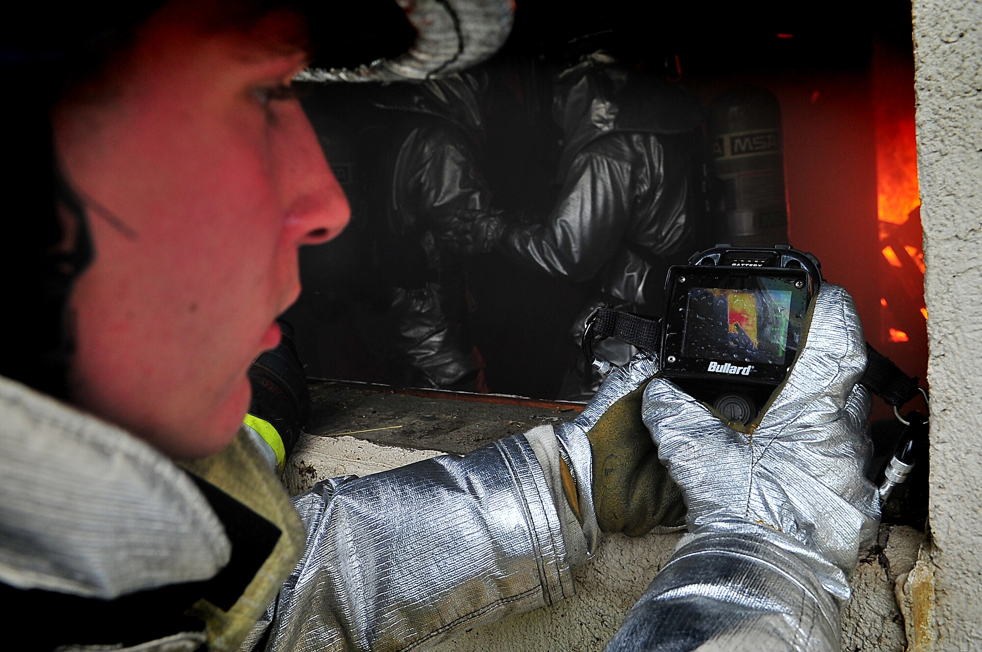 An Airman from the 51st Civil Engineer Squadron, uses a thermal scanner to detect rather there is a body in the fire during Silver Flag, Aug. 16. During Silver Flag members conducted six evolutions which consisted of eliminating the fire and hydraulic ventilation while putting on their JS-List suits underneath their fire fighting uniforms, which increases their core body temperature by 10 degree. Airmen from the 51st Civil Engineer Squadron, examine the aftermath of a Js-List structural fire during Silver Flag, Aug. 16. Once all fires are extinguished the Airmen will then proceed to search for any signs of victims that need to be evacuated. (U.S. Air Force photo/Staff Sgt. Daylena Gonzalez) 
