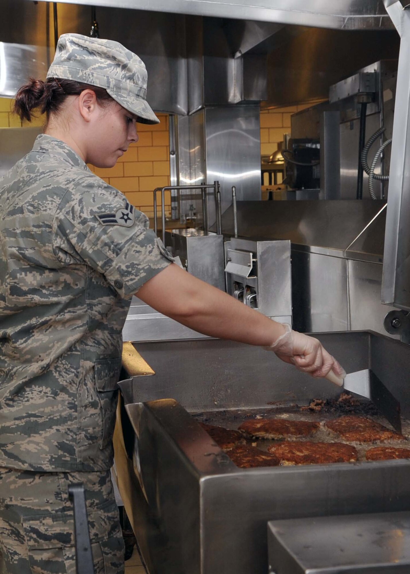 ALTUS AIR FORCE BASE, Okla.—Airman 1st Class Tori Bauer, 97th Force Support Squadron food service specialist, grills country fried steaks for lunch at the Solar Inn Dining Facility, Aug. 12, 2011. The facility offers a number of menu options for their customers such as Mongolian barbecue and Italian and American dishes. (U.S. Air Force photo by Senior Airman Leandra D. Stepp / 97th Air Mobility Wing / Public Affairs / Released)