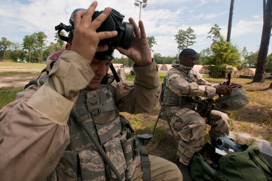 U.S. Air Force Airman 1st Class Justin Polk, 23rd Civil Engineer Squadron augmentee, left, and Airman 1st Class Jirah Petty, 23rd Security Forces Squadron, remove their gas masks after returning to a lower mission-oriented protective posture (MOPP) level during a phase II operational readiness exercise. MOPP levels are used to let Airmen know the amount of personal protective equipment needed to defend against possible chemical attacks. (U.S. Air Force Photo by Staff Sgt. Joshua J. Garcia/Released)