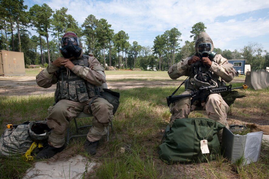 U.S. Air Force Airman 1st Class Justin Polk, 23rd Civil Engineer Squadron augmentee, left, and Airman 1st Class Jirah Petty, 23rd Security Forces Squadron, don their gas masks during a simulated attack while participating in a phase II operational readiness exercise (ORE). During the ORE, Airmen trained on performing their duties while remaining competent during chemical and biological attacks. (U.S. Air Force Photo by Staff Sgt. Joshua J. Garcia/Released)