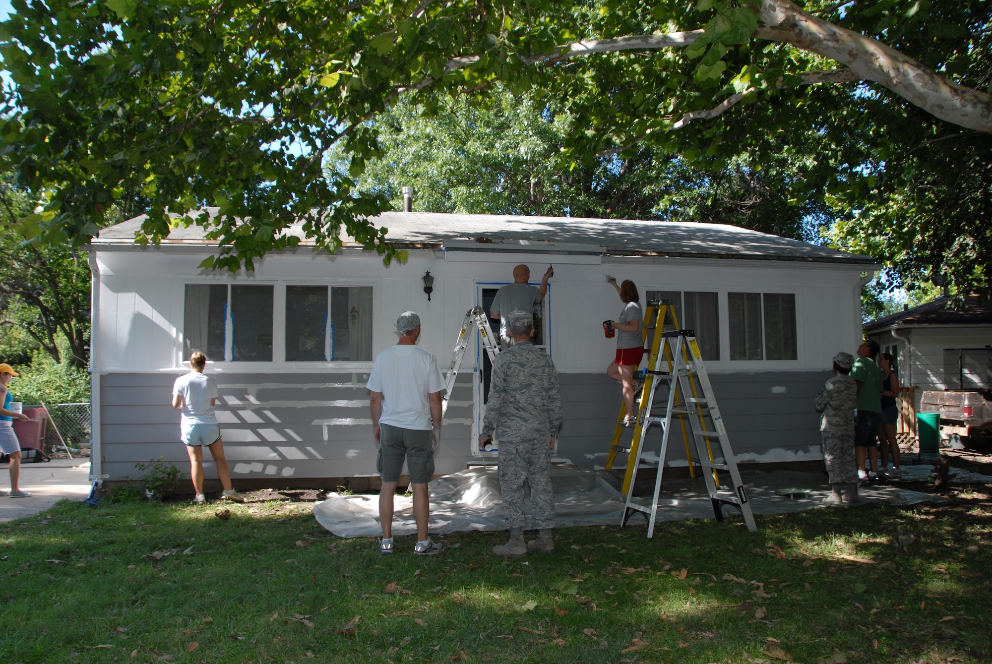 Members from the Nebraska Air and Army National Guard paint a house during the Lincoln Paint-a-thon hosted by Brush Up Nebraska in Lincoln, Neb. on Aug. 13, 2011. The home owners applied for this program through the Lincoln Action Program in 2010 and were approved in 2011.  (Nebraska Air National Guard photo by Airman First Class Mary Thach) (Released)