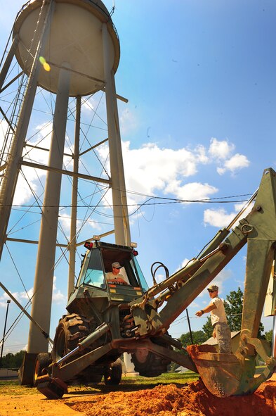 U.S. Air Force Senior Airman Steve Williams and Senior Airman Brian King, 20th Civil Engineer Squadron heavy equipment operators, work together to remove clay around  broken water pipes using a backhoe at Shaw Air Force Base, S.C., Aug. 16, 2011. The Rhodes Water Tower next to Highway 441 remains the backup water reservoir for Shaw's main water tower near the enlisted dormitories. After repairs are completed, a water sample will be taken to test the levels of purity, phosphates, acidity and alcoholicity to ensure a fresh water supply is available.  (U.S. Air Force photo/Airman 1st Class Neil D. Warner)(Released)