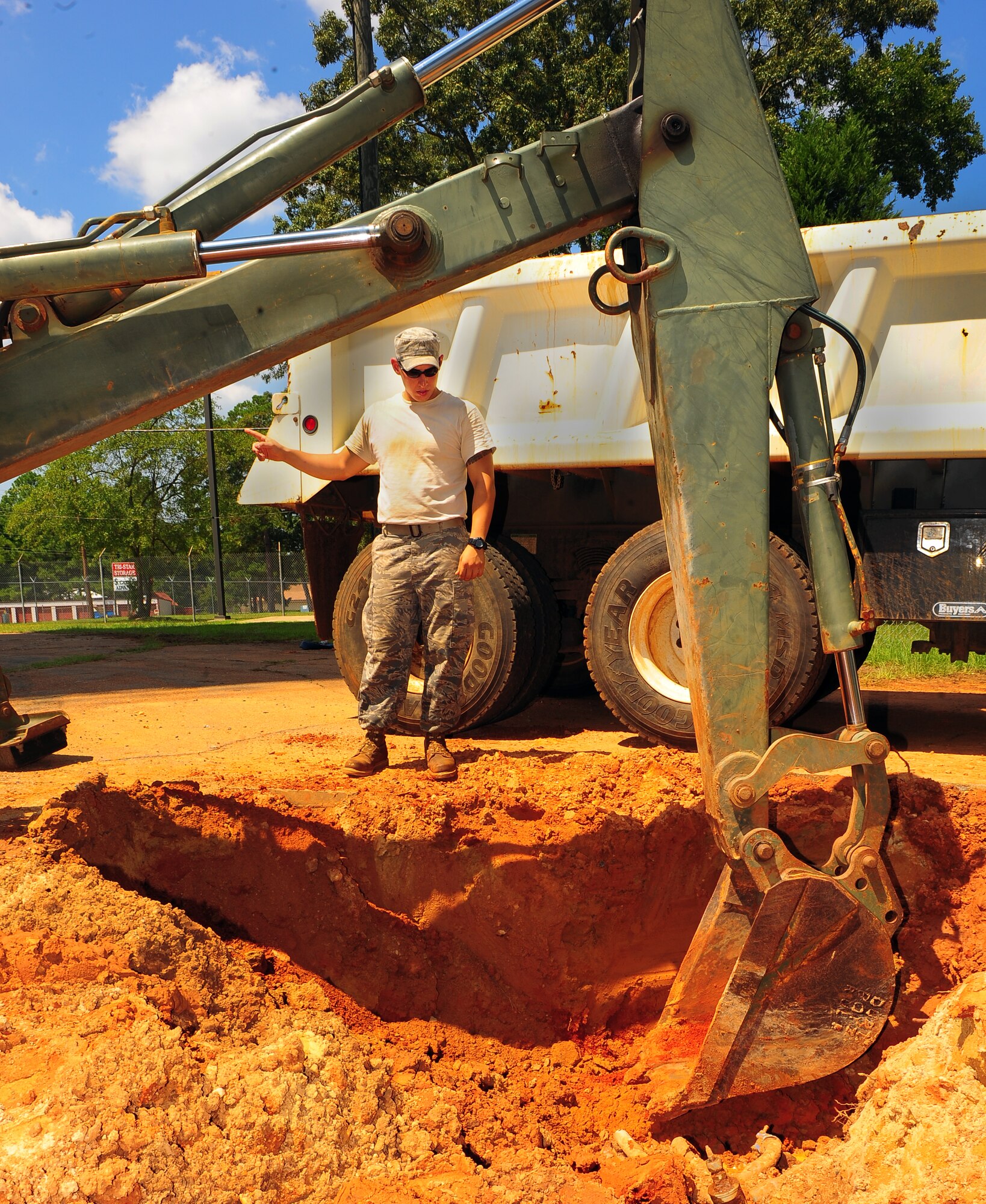 U.S. Air Force Senior Airman Brian King, 20th Civil Engineer Squadron heavy equipment operator, gives guidance for navigating the backhoe around the water pipes at Shaw Air Force Base, S.C., Aug. 16, 2011. The Rhodes Water Tower next to Highway 441 remains the backup water reservoir for Shaw's main water tower near the enlisted dormitories. After repairs are completed, a water sample will be taken to test the levels of purity, phosphates, acidity and alcoholicity to ensure a fresh water supply is available.  (U.S. Air Force photo/Airman 1st Class Neil D. Warner)(Released)