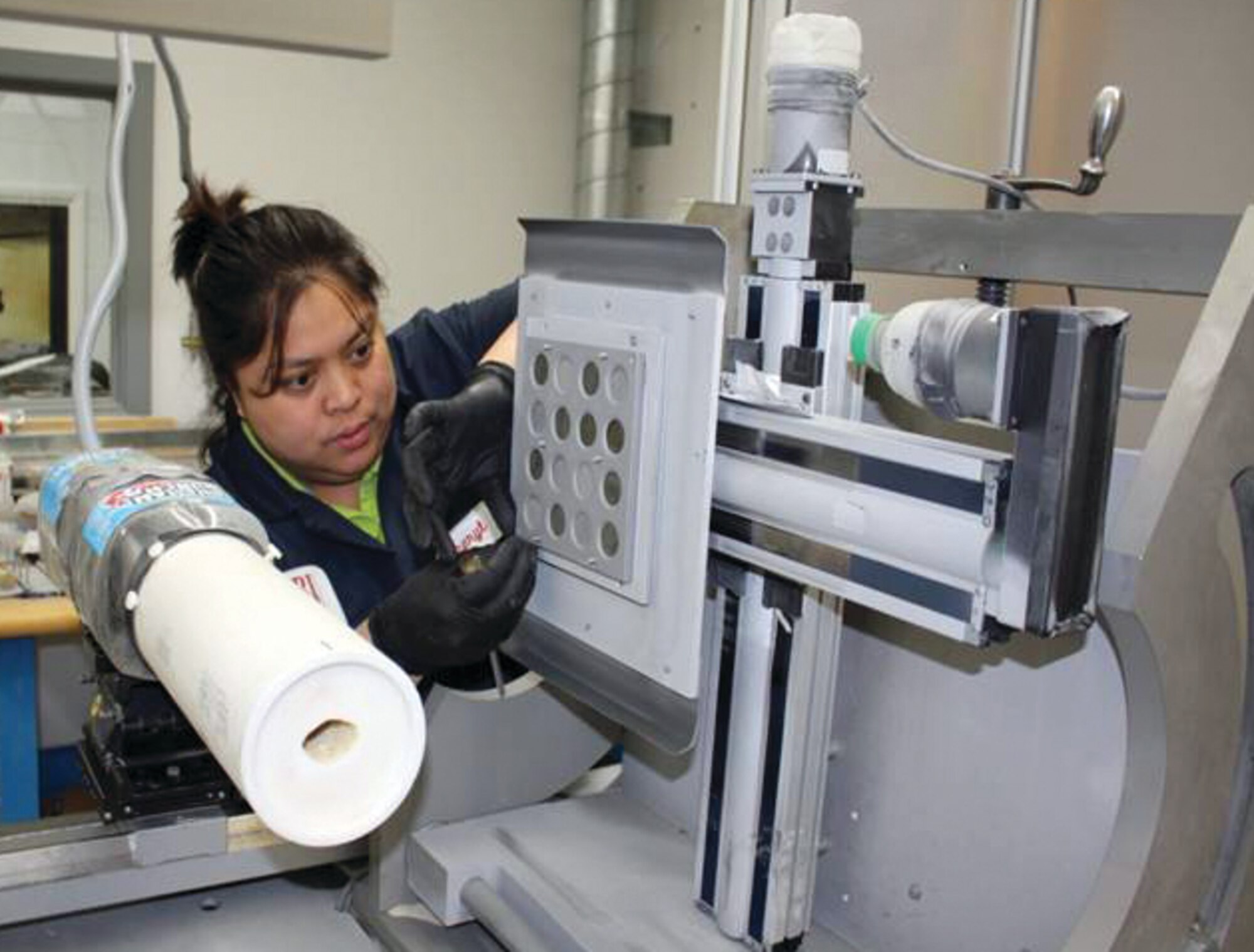 AFRL/UDRI’s Cheryl Castro installs samples for sand erosion testing in the test rig.  Today’s desert sand is different from the sand used in characterization standards that have been trusted for decades.