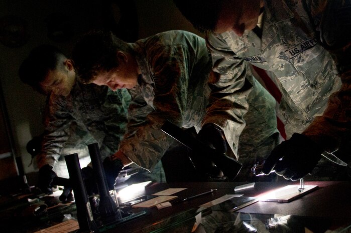 Staff Sgt. Michael Zimmerman, Tech. Sgt. Shelly Branch and Staff Sgt. Daniel Owen learn how to capture the texture and depth of a fingerprint in a photograph during Battlefield Forensics training at Joint Base Charlesto - Air Base Aug. 17. (U.S.  Air Force photo/ Myles Cullen)