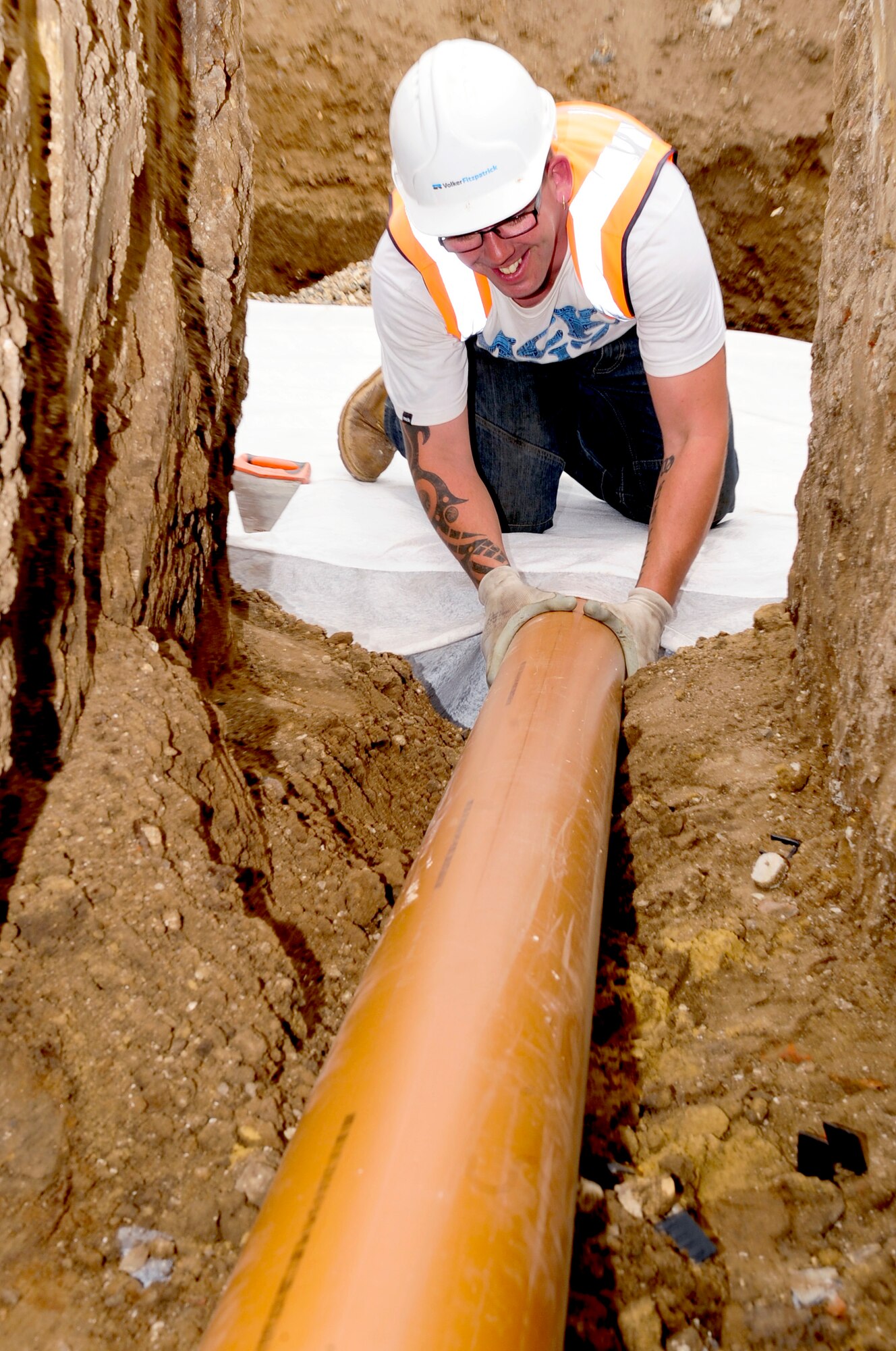 RAF MILDENHALL, England – Simon Santos, a local contractor, attaches a drainage pipe to a completed cellular soakaway drainage system as part of the Lincoln Road construction here Aug. 17, 2011. The soakaway system allows for storm water to be held and released slowly back into the ground decreasing the amount of pollution entering the public drainage system. (U.S. Air Force photo/Senior Airman Ethan Morgan)