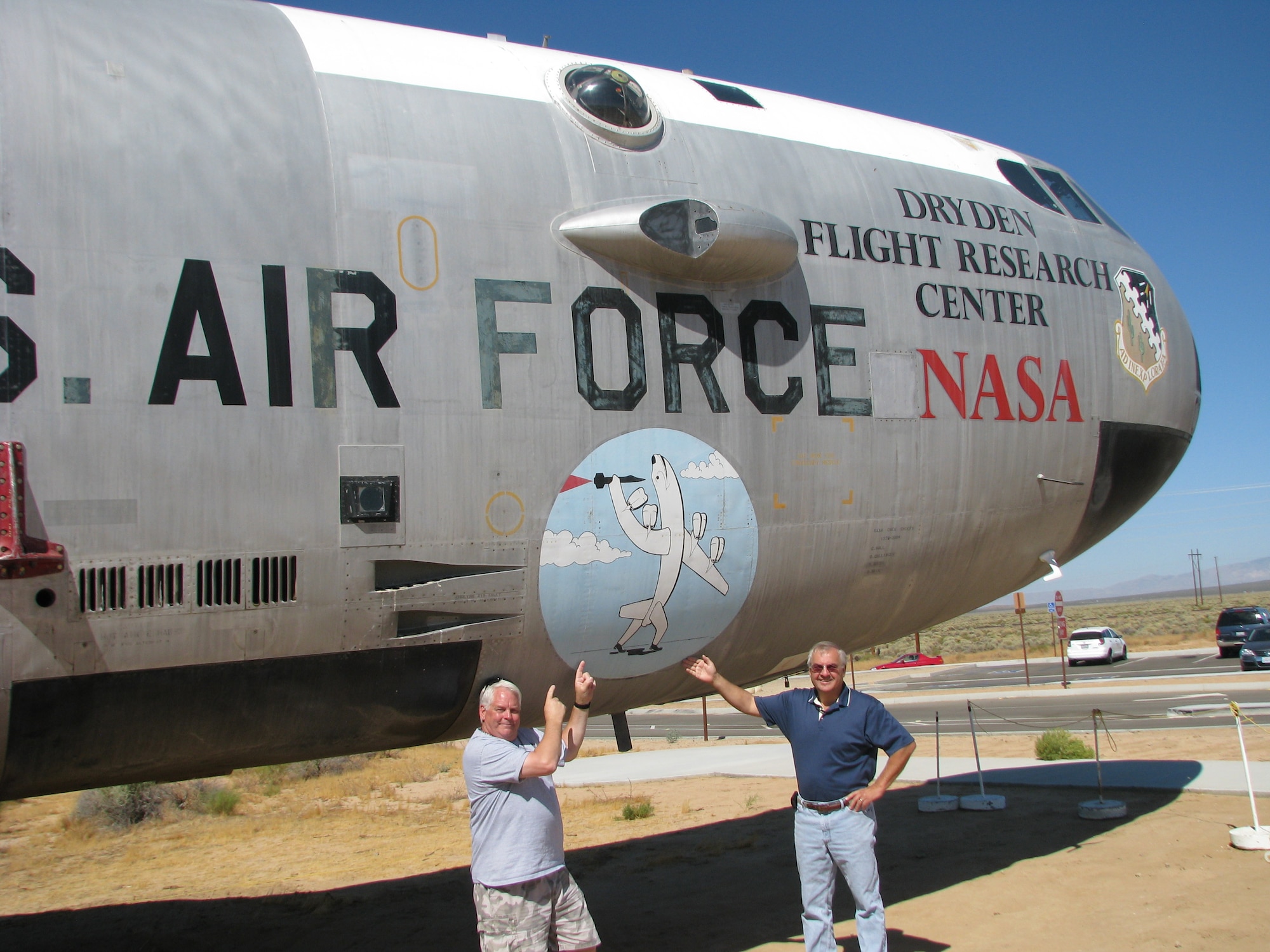 Tony Moore (left) a specialist at the Air Force Flight Test Center Museum, and George Welsh, AFFTC Museum director/curator, point to a humorous drawing that the crew of Ship 008 had painted on the side of the aircraft. The drawing depicts the NB-52B “throwing” an X-15 into flight. The bomber is on display at Edwards’ North Gate. (Air Force photo by Diane Betzler)