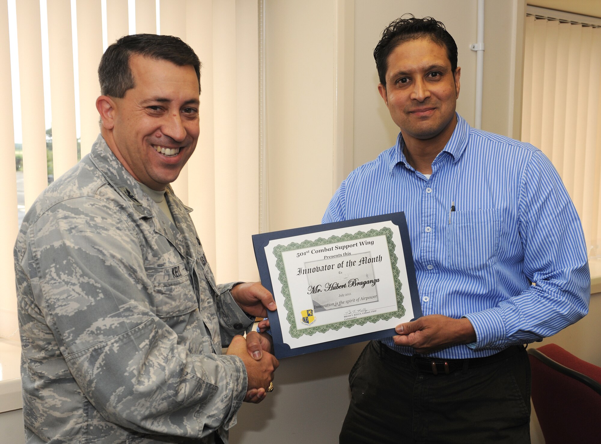 RAF ALCONBURY, United Kingdom - Col. Brian Kelly, 501st Combat Support Wing commander, presents the Innovator of the Month award to Hubert Braganza, 423rd Civil Engineer Squadron. Braganza's identified that American appliances should no longer be delivered to houses on the British economy resulting in significant savings in energy, water and overall cost of the appliance. (U.S. Air Force photo by Senior Airman Joel Mease)