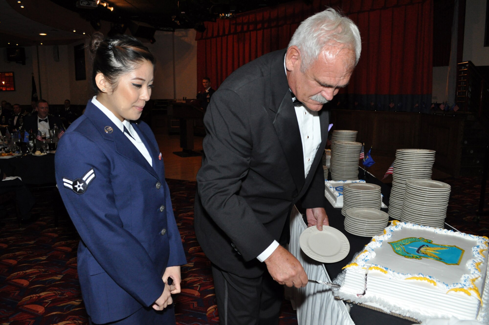 RAF MILDENHALL, England – Retired Col. Steve Connelly, a prior commander of the 352nd Special Operations Group, slices the first piece of cake for Airman 1st Class Marie Kris Toledo, 321st Special Tactics Squadron, who was the youngest Airman in attendance at the Air Commando Ball, held July 30, 2011, at the Galaxy Club.  More than 200 members (made up of members from the Joint Special Operations Air Component-Europe and 352 SOG and their spouses) attended the event, which celebrated the history and heritage of the 2nd Air Commando Group.  Connelly was the guest speaker at the event.  (U.S. Air Force photo/Tech. Sgt. Marelise Wood)