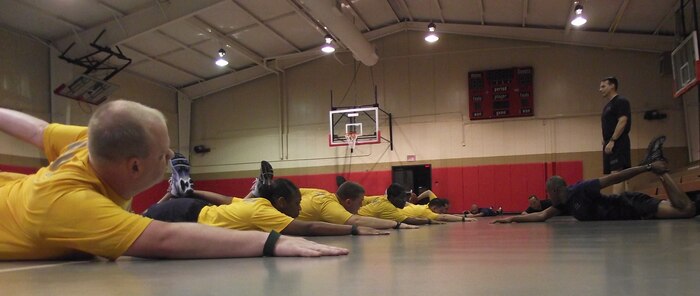 Chief Petty Officer selectees go through a stretching routine under the watchful eyes of Command Master Chief Billy Cady at the Joint Base Charleston - Weapons Station gym last week. Physical training plays an important role in the Induction process as first class petty officers make the transition to chief petty officers. Cady is the command master chief of the Naval Support Activity. (U.S. Navy photo) 