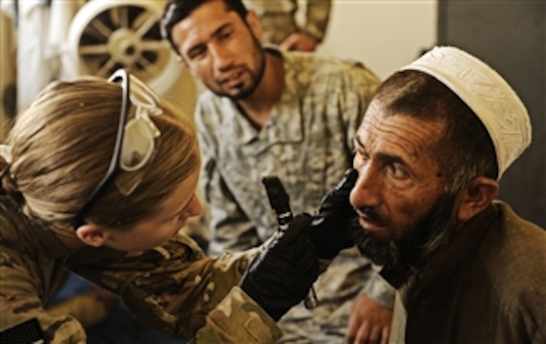 U.S. Air Force Senior Airman Lauren Everett (left), a medical technician assigned to Laghman Provincial Reconstruction Team, examines the injured eye of an Afghan Uniformed Police officer at the Mehtar Lam police headquarters in Laghman province, Afghanistan, on Aug. 13, 2011.  The Provincial Reconstruction Team and a security forces assistance team traveled to the police headquarters to provide medical care to local policemen and to meet with the police-training officer.  