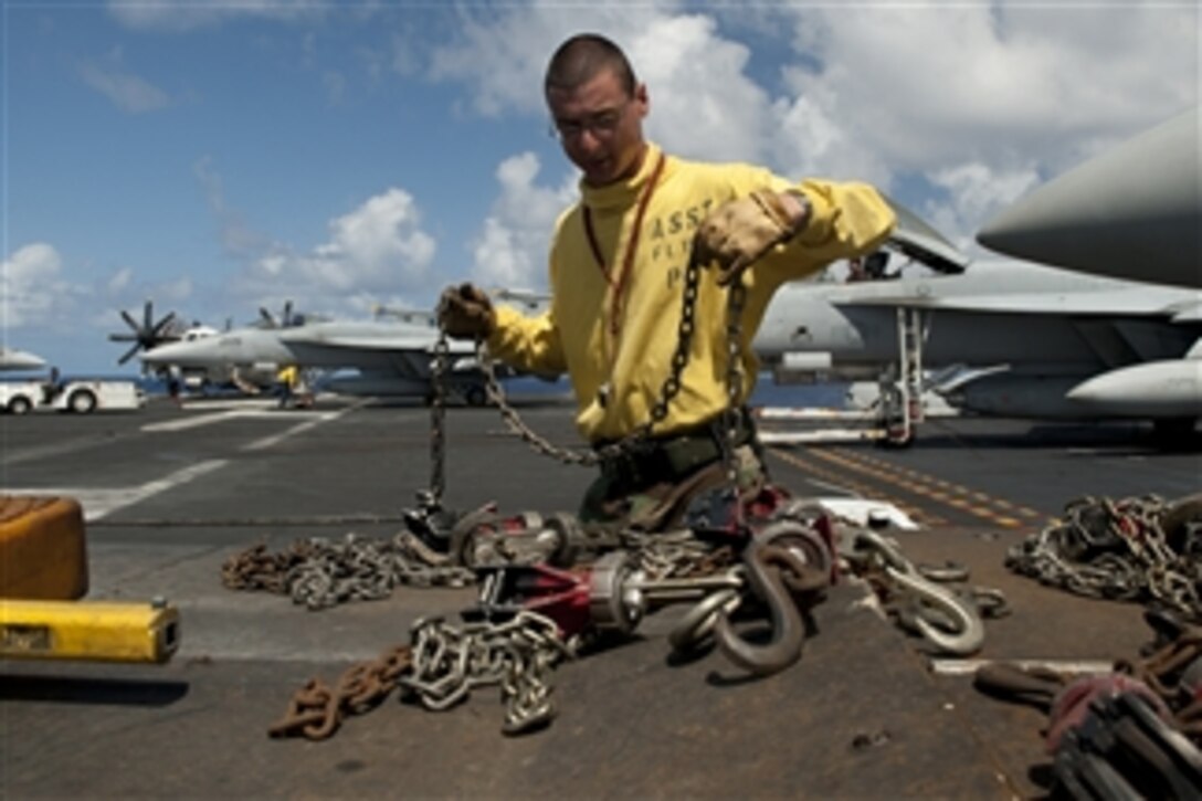 U.S. Navy Petty Officer 2nd Class Adam Zimniak collects chains removed from an F/A-18E Super Hornet aircraft aboard the aircraft carrier USS John C. Stennis (CVN 74) while underway in the Pacific Ocean on Aug. 16, 2011.  The John C. Stennis Carrier Strike Group is on a western Pacific Ocean and Persian Gulf deployment.  