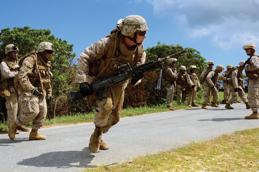 Pfc. Matthew E. Oldham, middle, picks up his M240B medium machine gun and moves toward the firing line Aug. 18. Oldham just completed a series of jumping jacks and pushups designed to increase his heart rate and make the training more realistic. He is a combat engineer with 9th Engineer Support Battalion, 3rd Marine Logistics Group, III Marine Expeditionary Force.