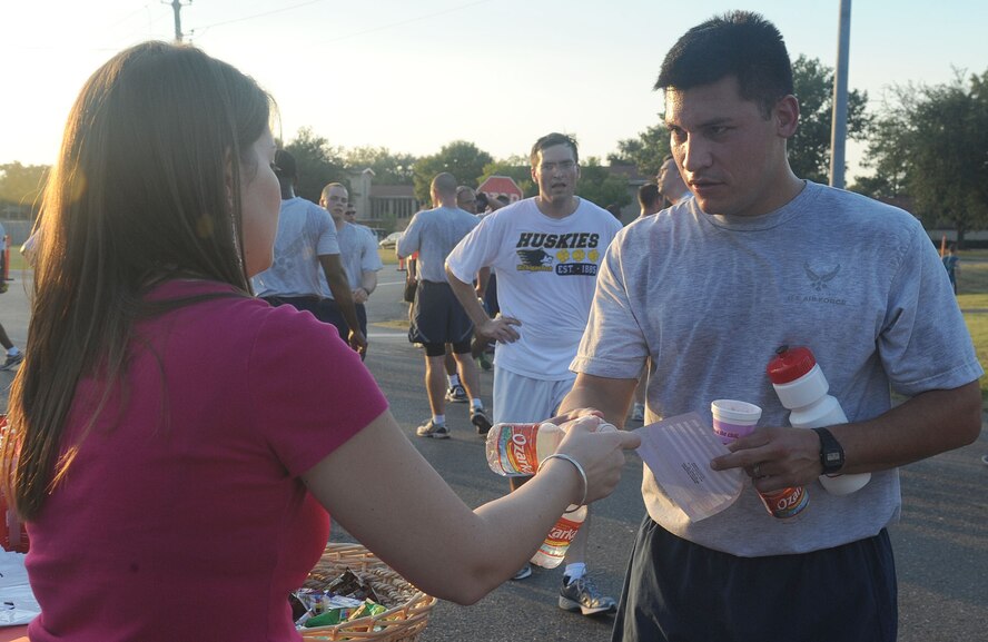 Ellie DiGacomo, from Bossier City, La., hands water to Senior Airman Joseph Senteno, 2nd Comptroller Squadron, after the "Back to School" fun run on Barksdale Air Force Base, La., Aug. 18. It's important to stay hydrated, especially after running long distances to prevent heat exhaustion and other related illnesses. (U.S. Air Force photo/Senior Airman Kristin High)(RELEASED)
